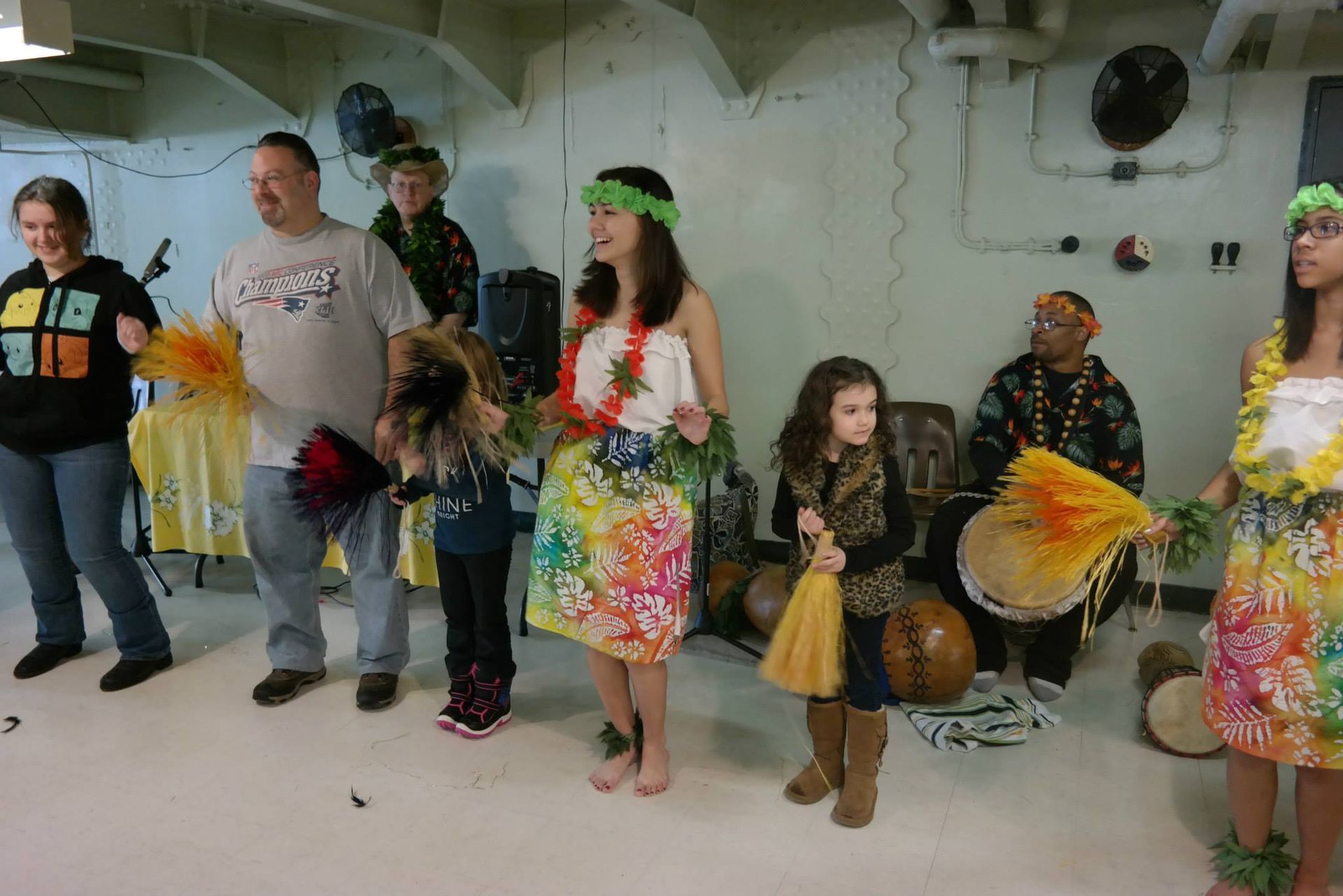A group of people dressed in hawaiian costumes are dancing in a room.
