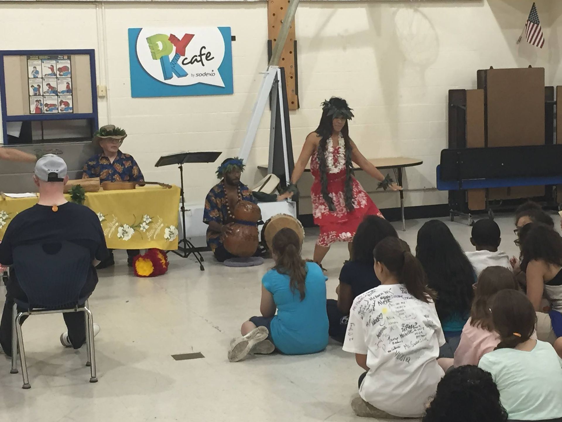 A group of people are sitting on the floor in front of a sign that says py cafe