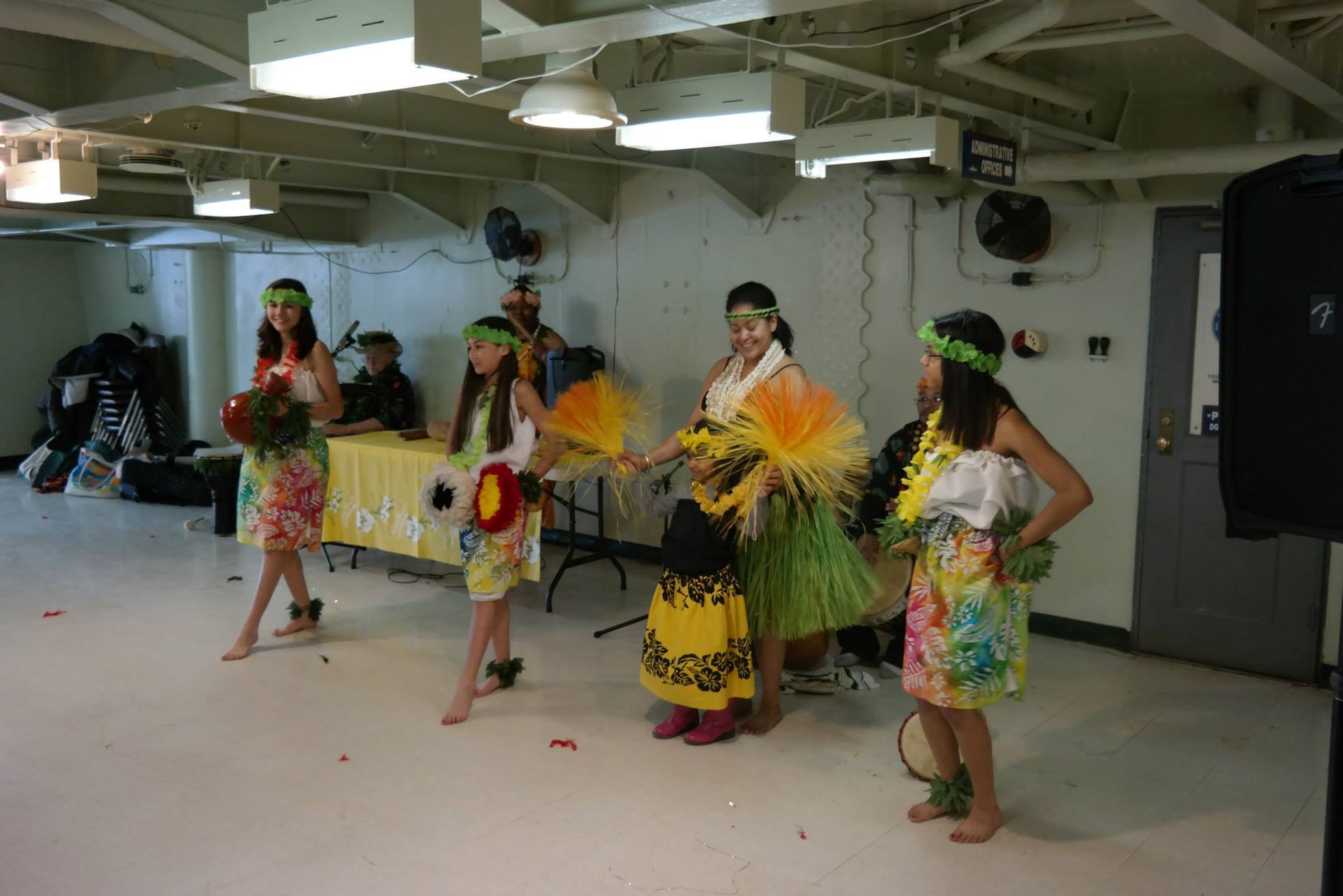 A group of young girls are dancing hula in a room