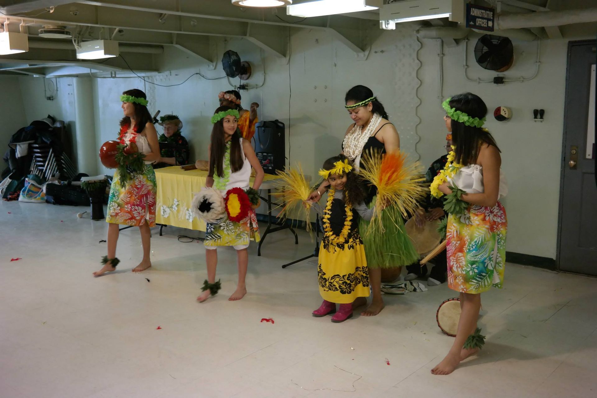A group of young girls are dancing hula in a room.