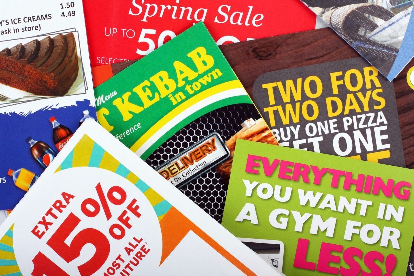 Assortment of colorful flyers promoting discounts for food, gyms, and spring sales.