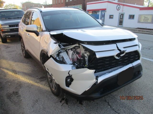 White SUV with significant front-end damage on a street, likely after a collision.