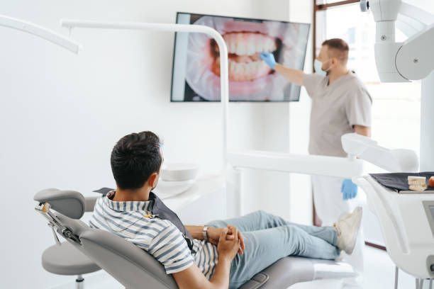 A dentist showing a patient the image of his teeth on the screen.
