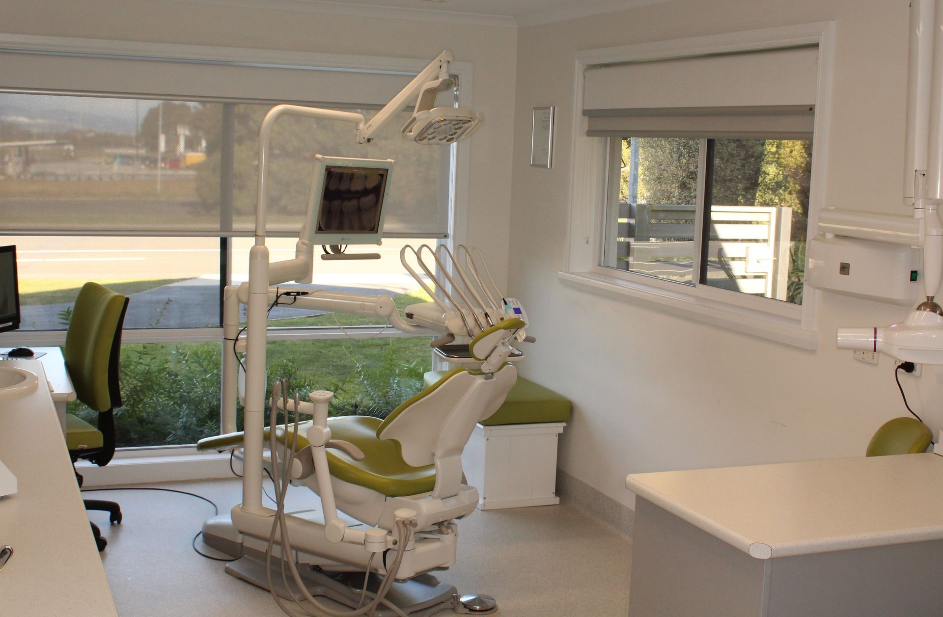 Three dentists in a dental office performing a procedure on a patient, under bright lights.