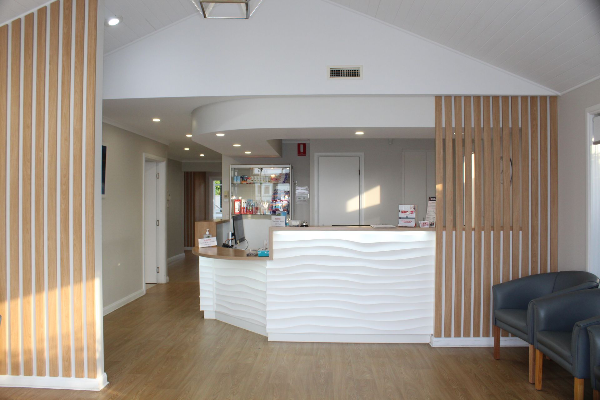 Woman smiles in a dentist chair while dentist in mask adjusts light.