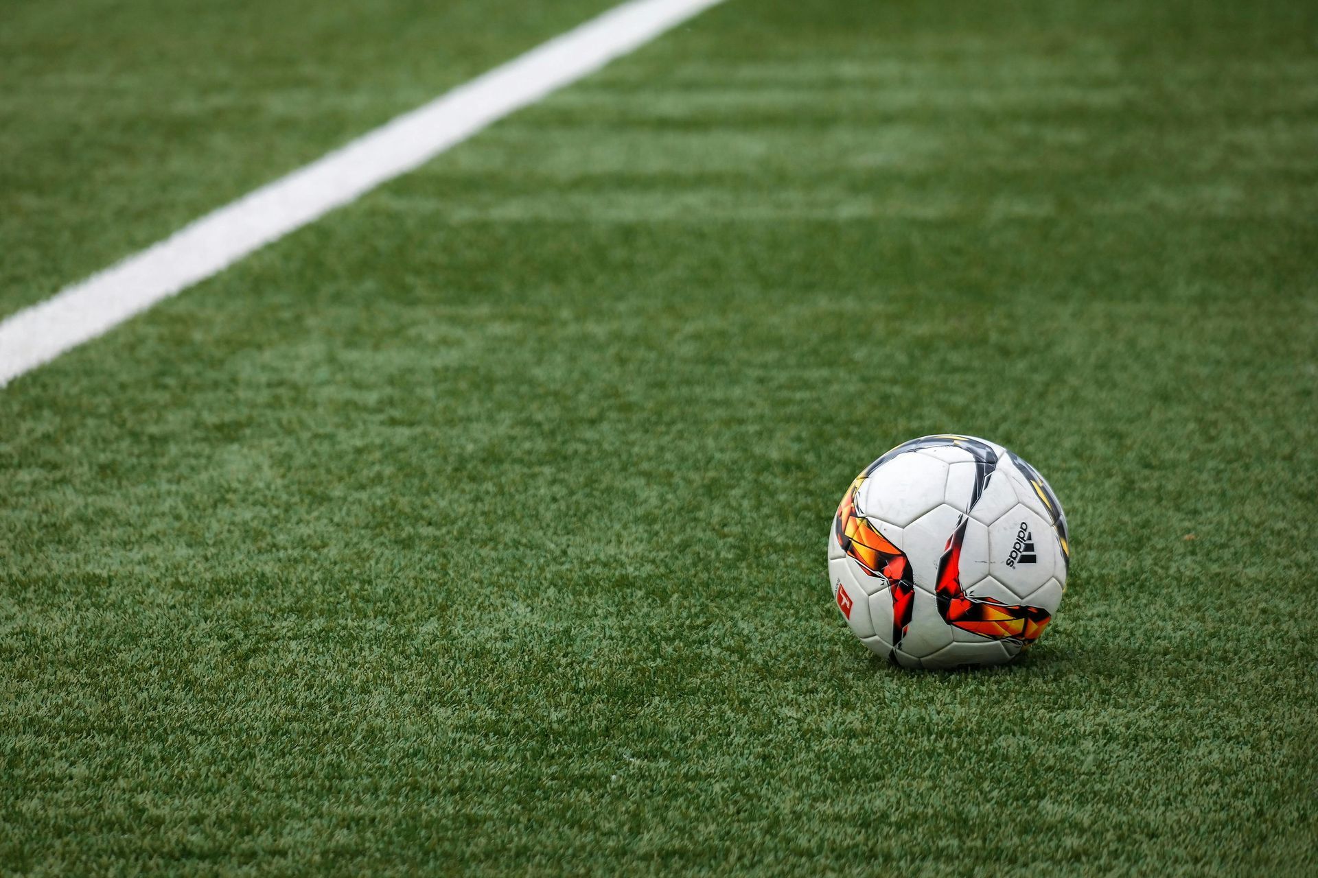 Soccer ball on a green field near a white line.