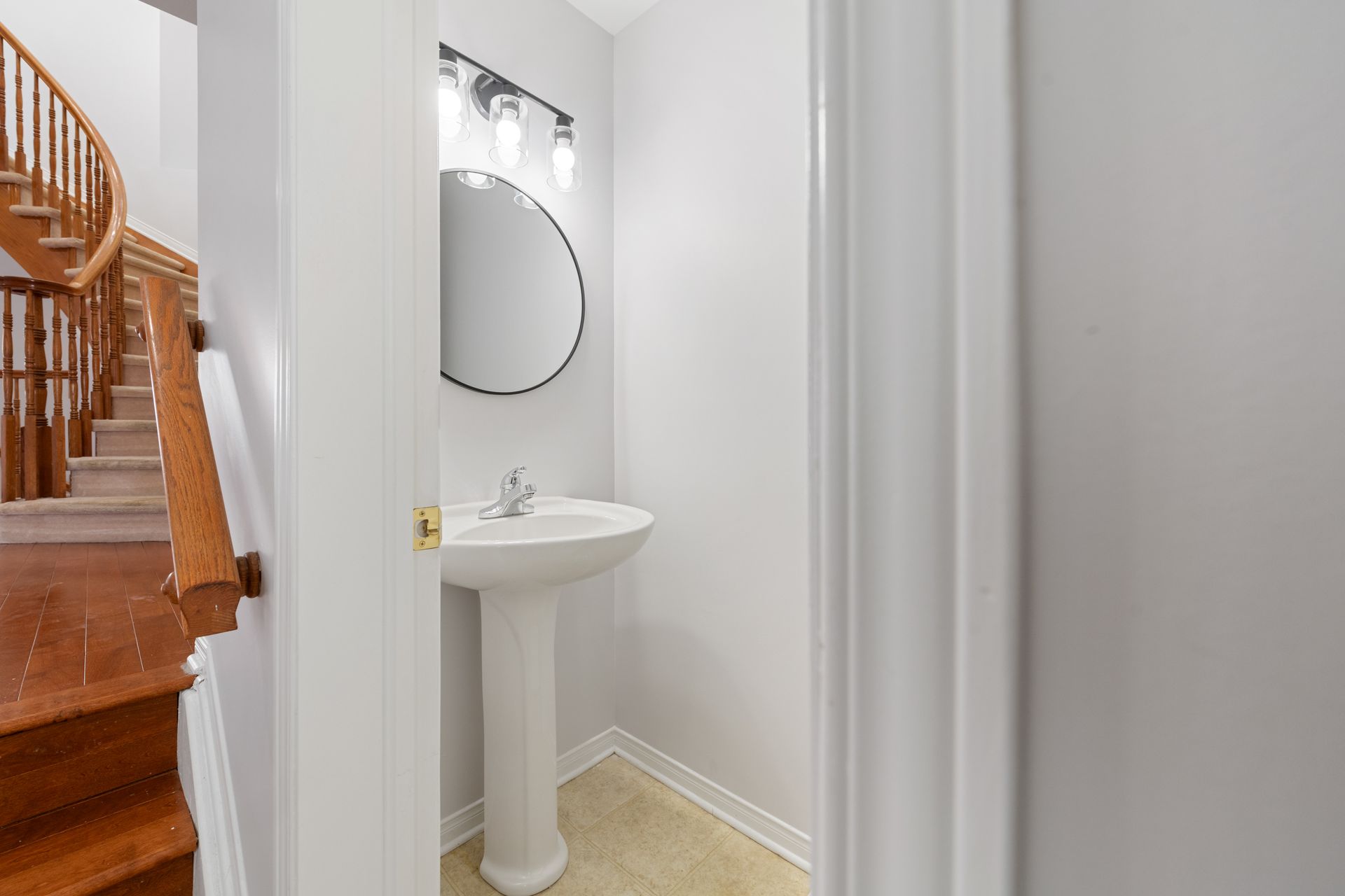 A bathroom with a sink , mirror and stairs.