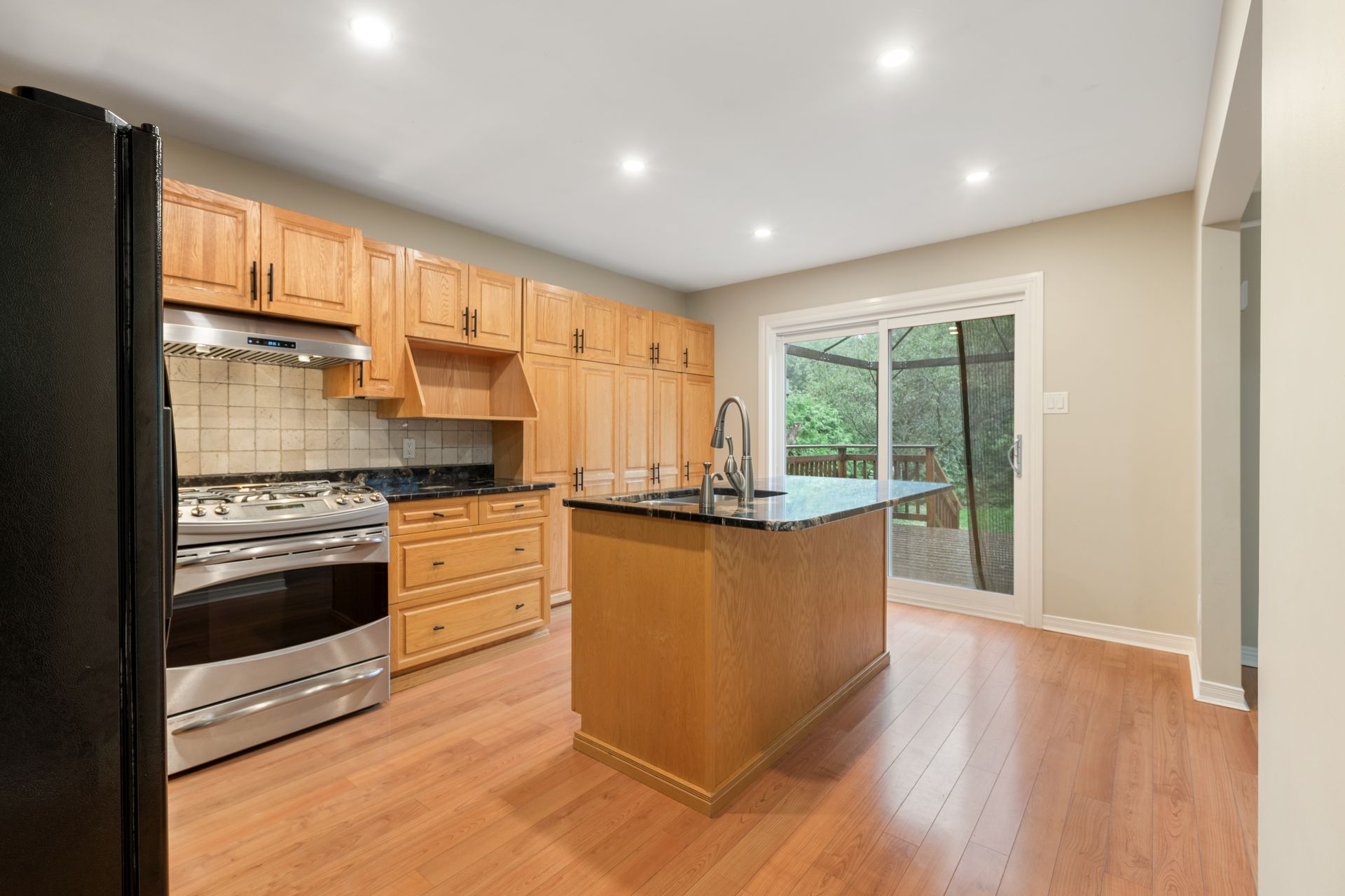 A kitchen with wooden cabinets , stainless steel appliances , and a large island.