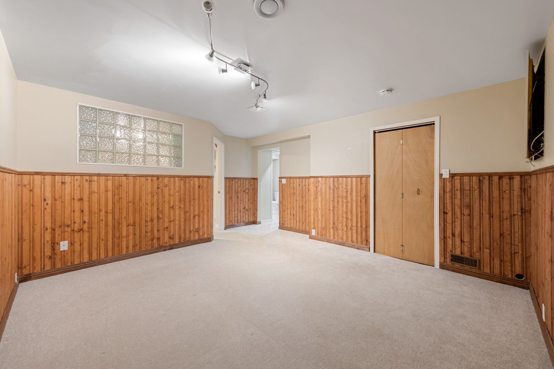 An empty room with wood paneling and a carpeted floor.