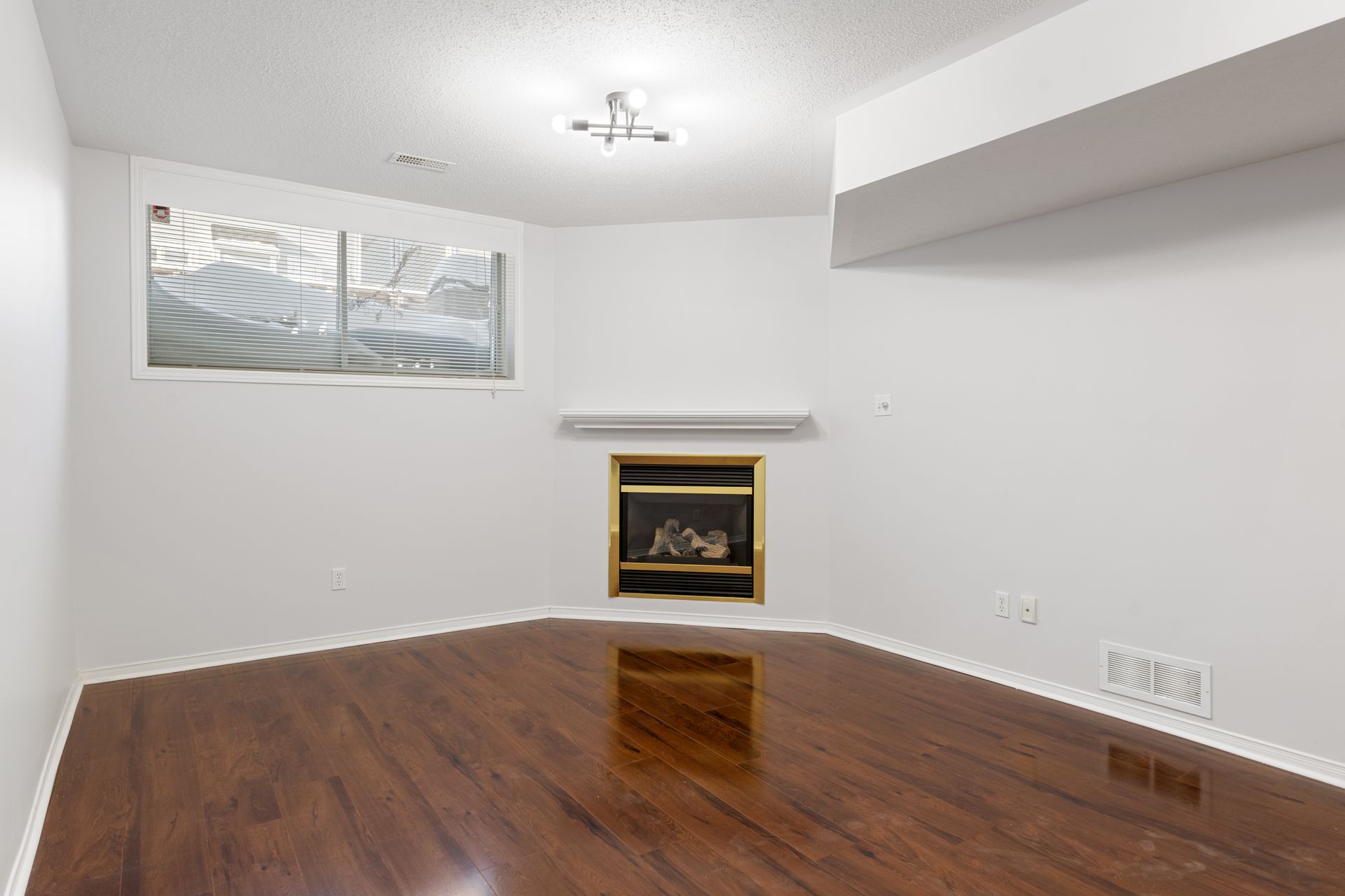 An empty living room with hardwood floors and a fireplace.