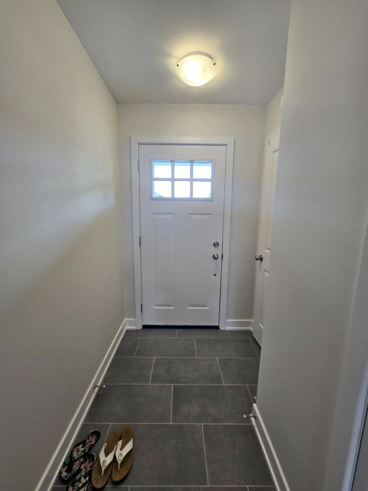 A hallway with a white door and flip flops on the floor