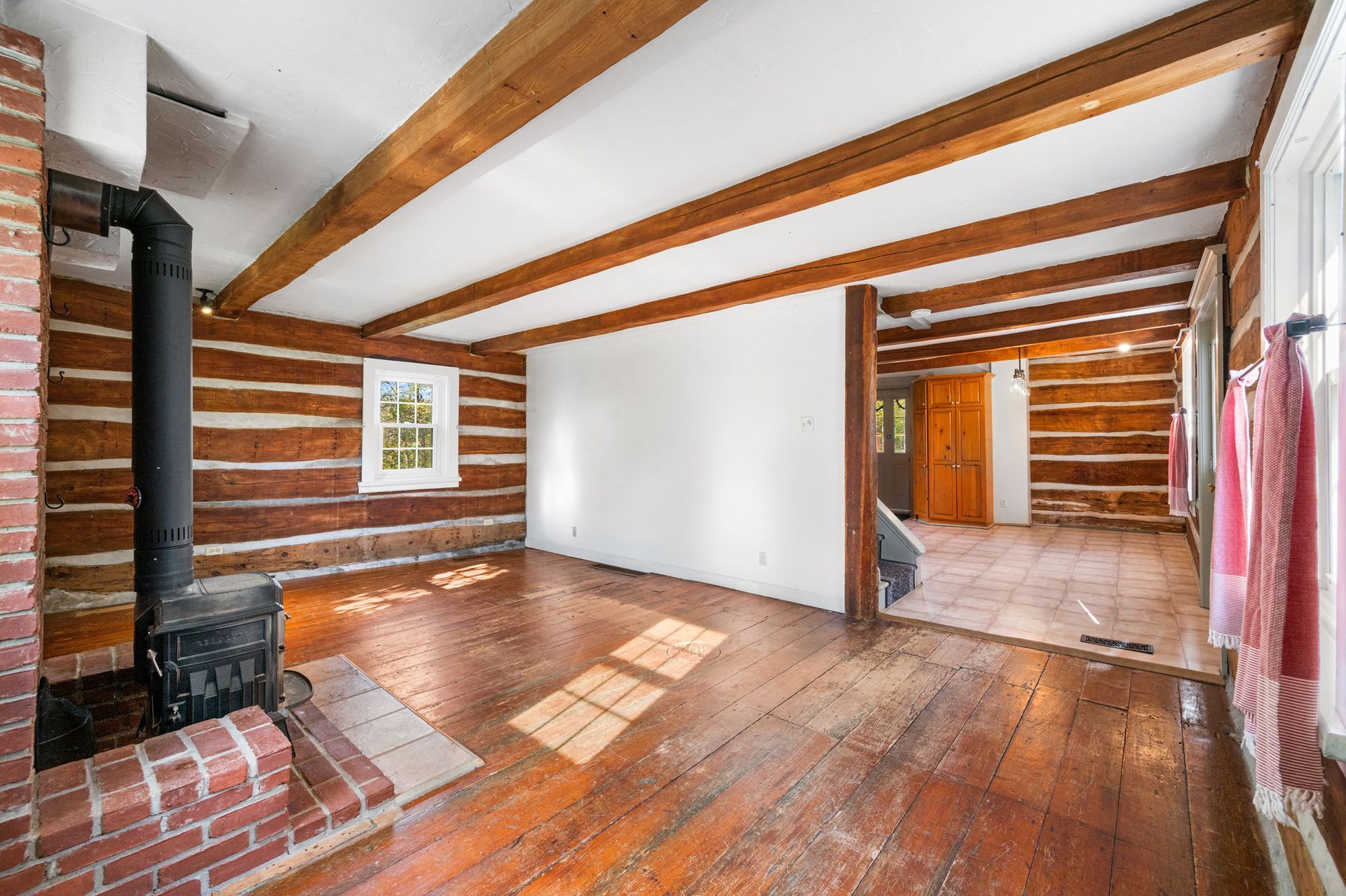 Rustic living room with exposed wood beams, log walls, and wood-burning stove.