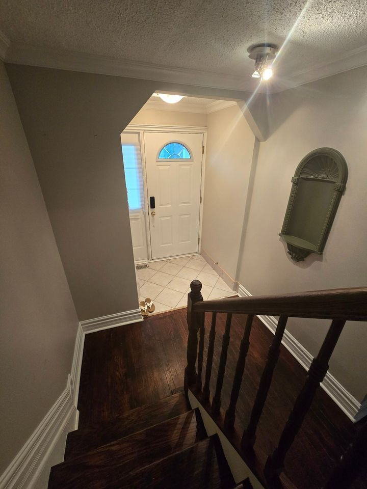 A hallway with stairs leading up to a door and a mirror on the wall.