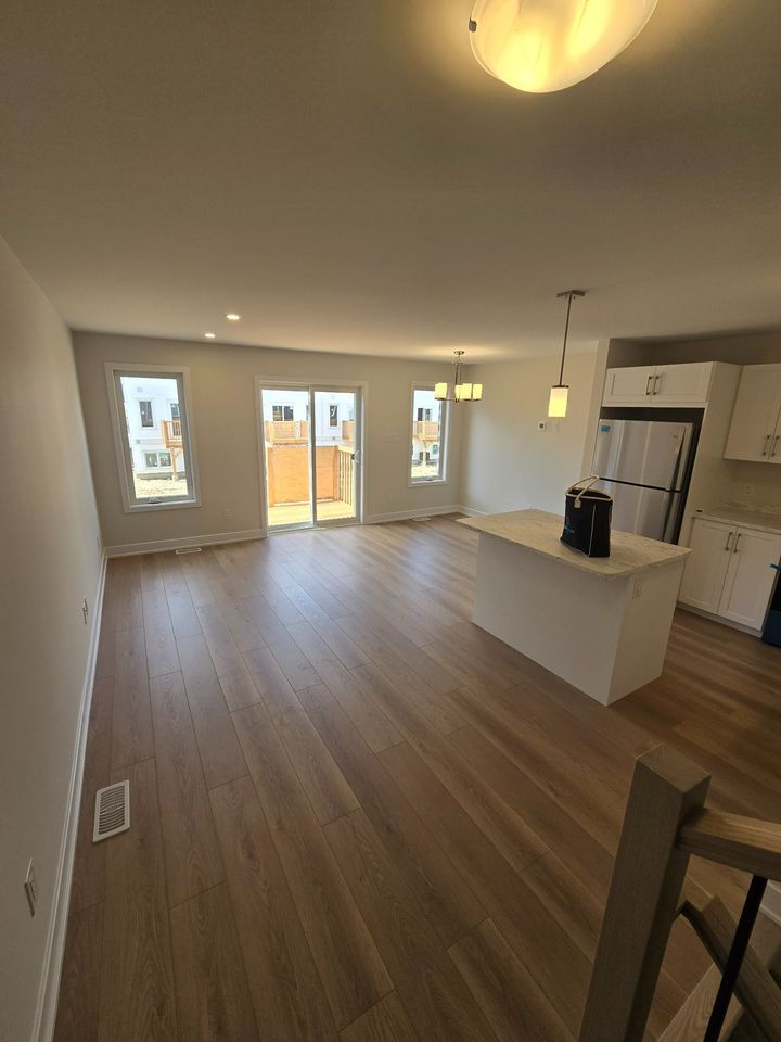 A large empty room with hardwood floors and a kitchen.