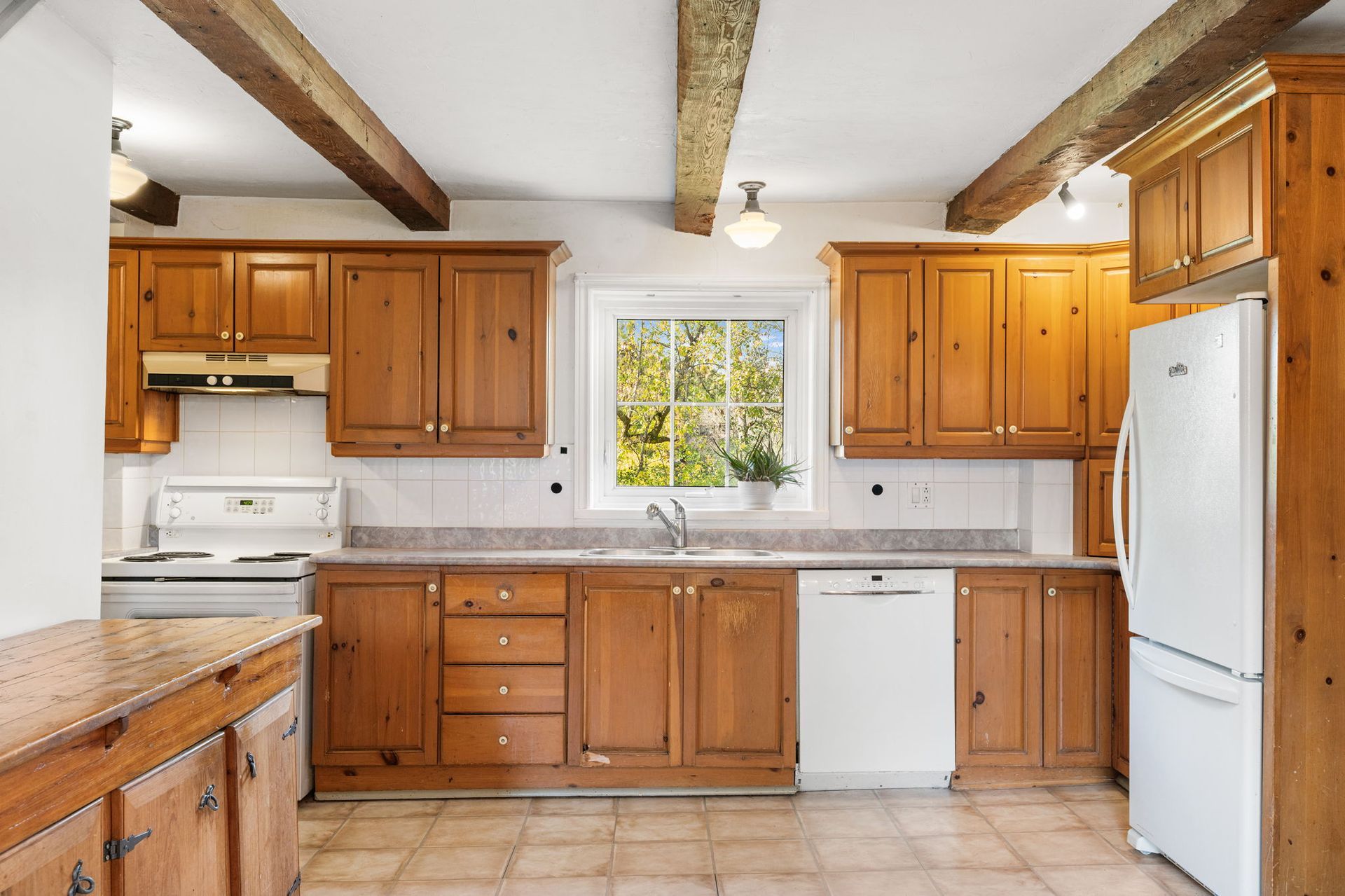 Wooden kitchen with matching cabinets, white appliances, and a window with a view.
