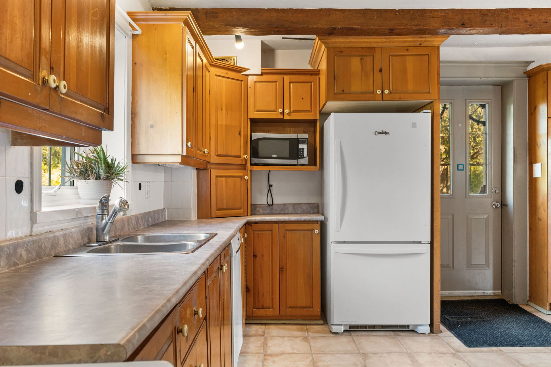 Kitchen with wood cabinets, light countertops, white refrigerator, and a door with glass panels.