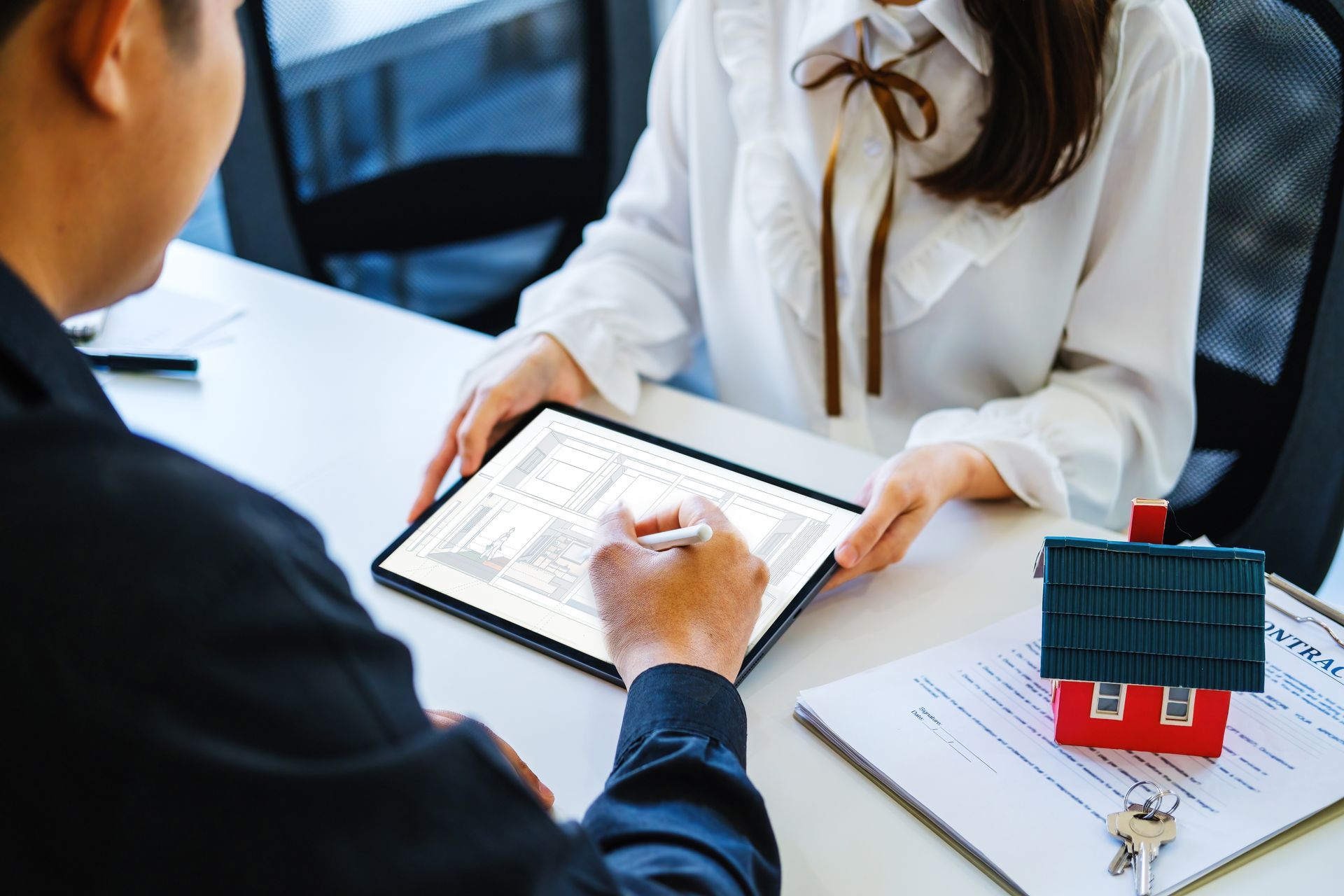 A man and a woman are sitting at a table looking at a tablet.