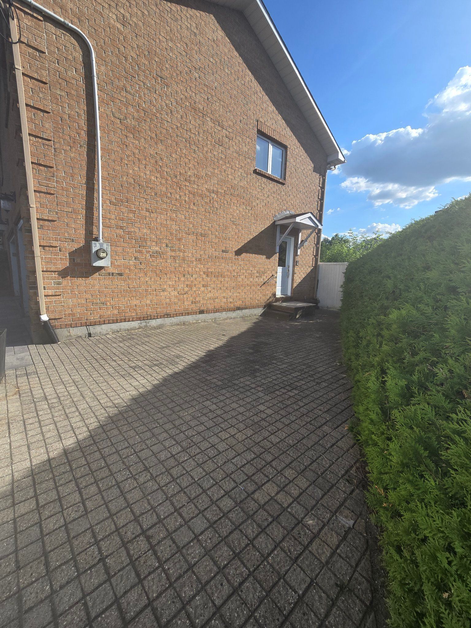A brick house with a white door and a brick walkway leading to it.