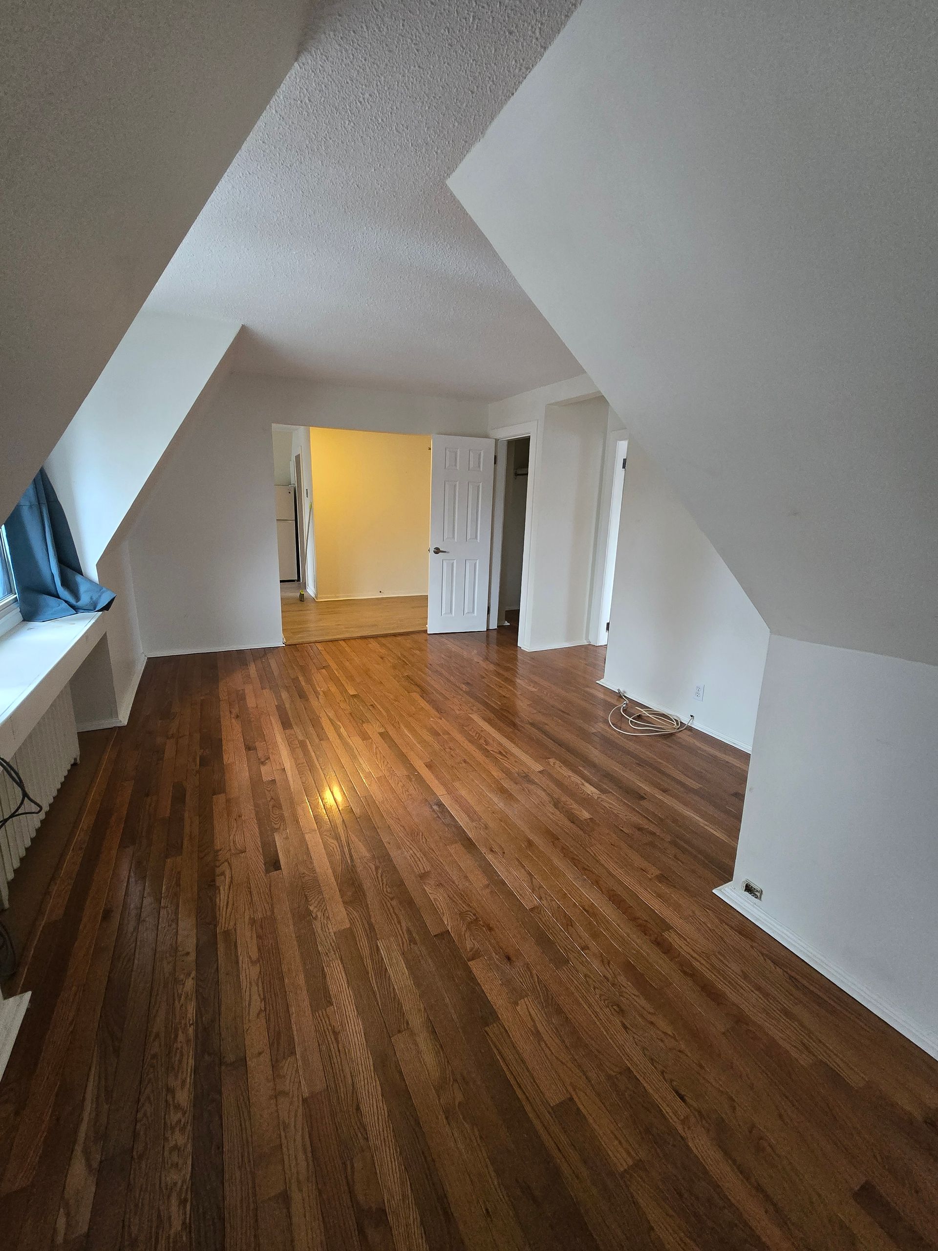An empty room with hardwood floors and white walls.