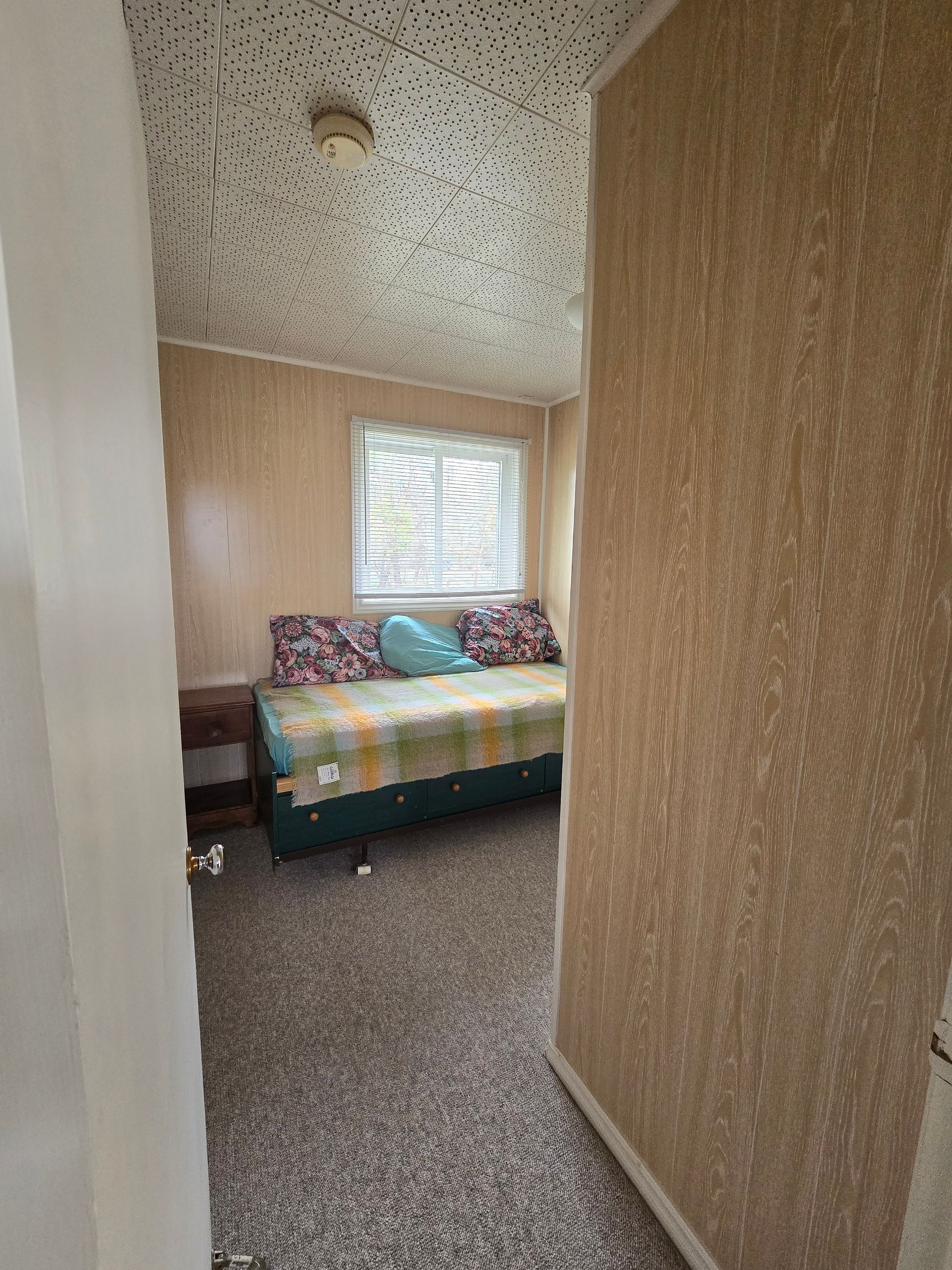 A bedroom with a bed , nightstand , and window.