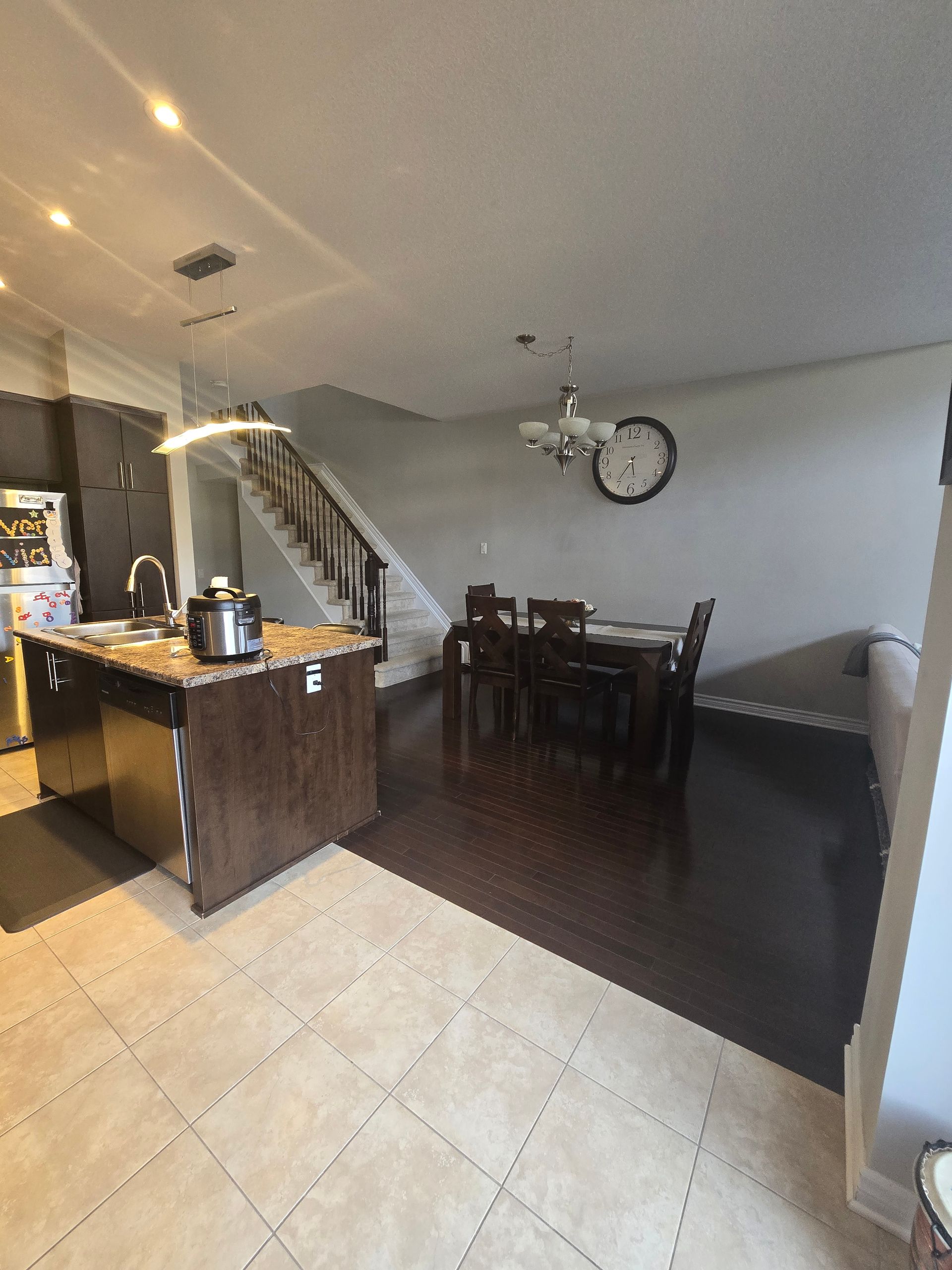 A kitchen and dining room in a house with a clock on the wall.