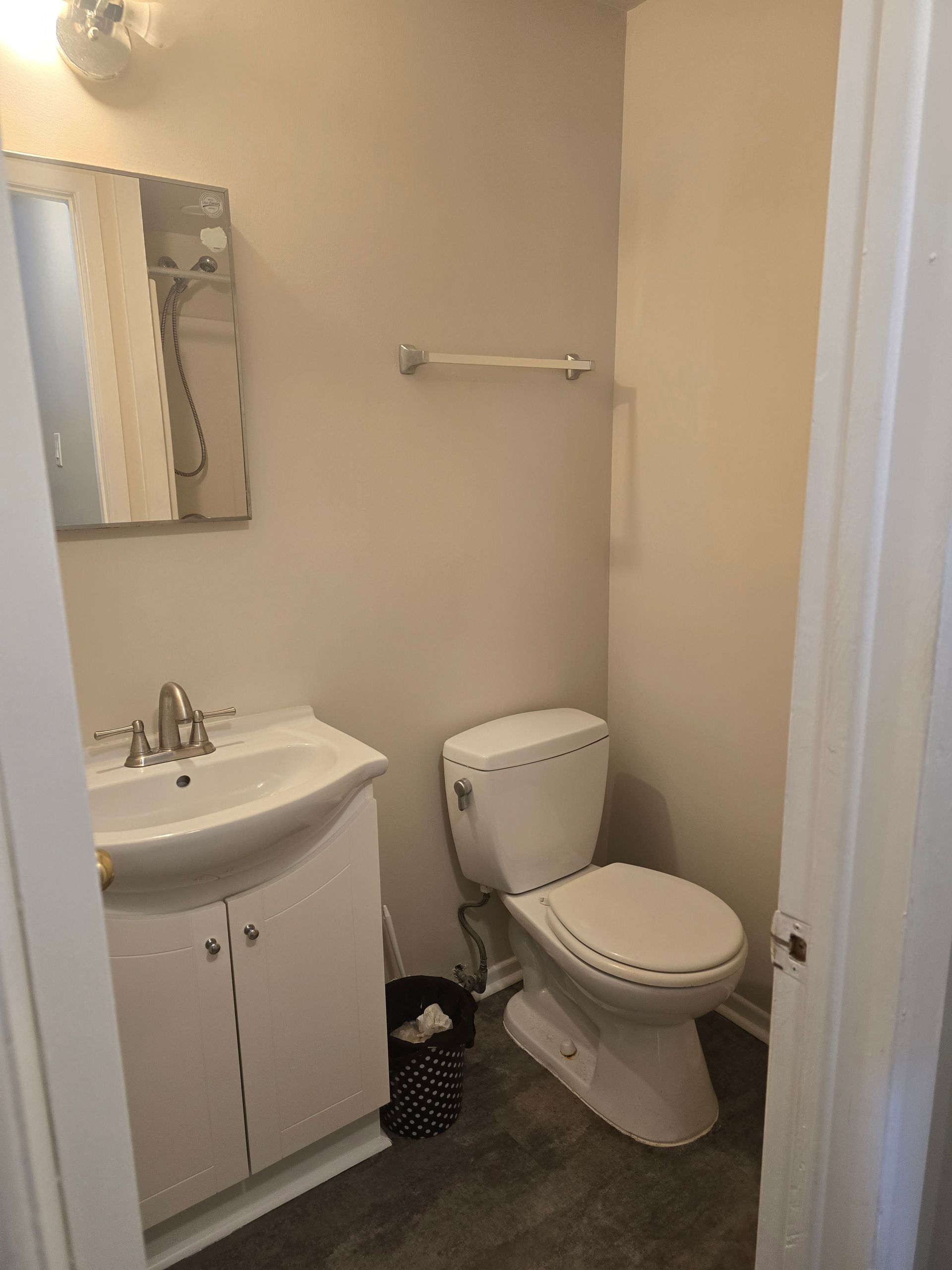 A bathroom with a toilet , sink and mirror.