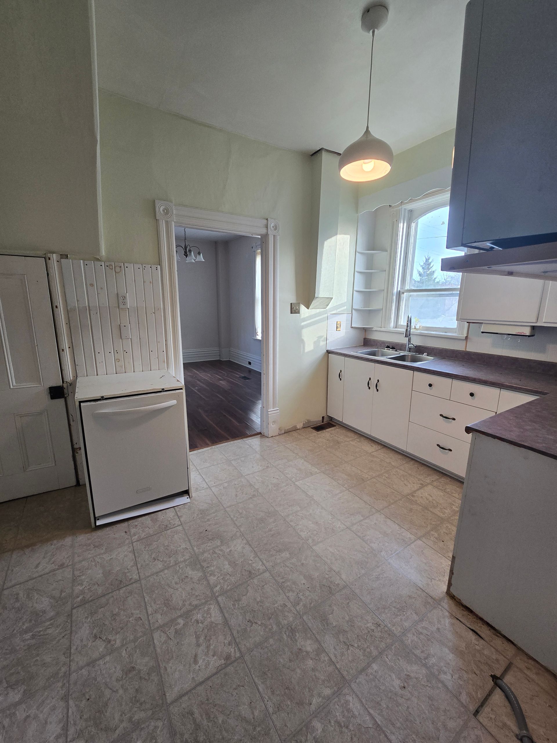 Kitchen with white appliances, cabinets, and a doorway to another room.