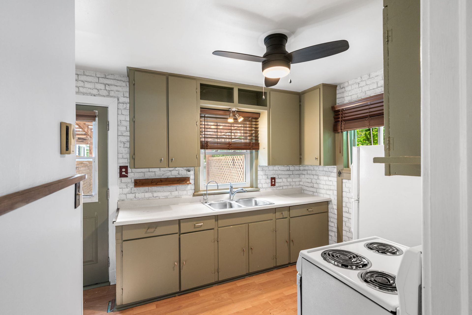 A kitchen with green cabinets, white brick backsplash, and a white stove.