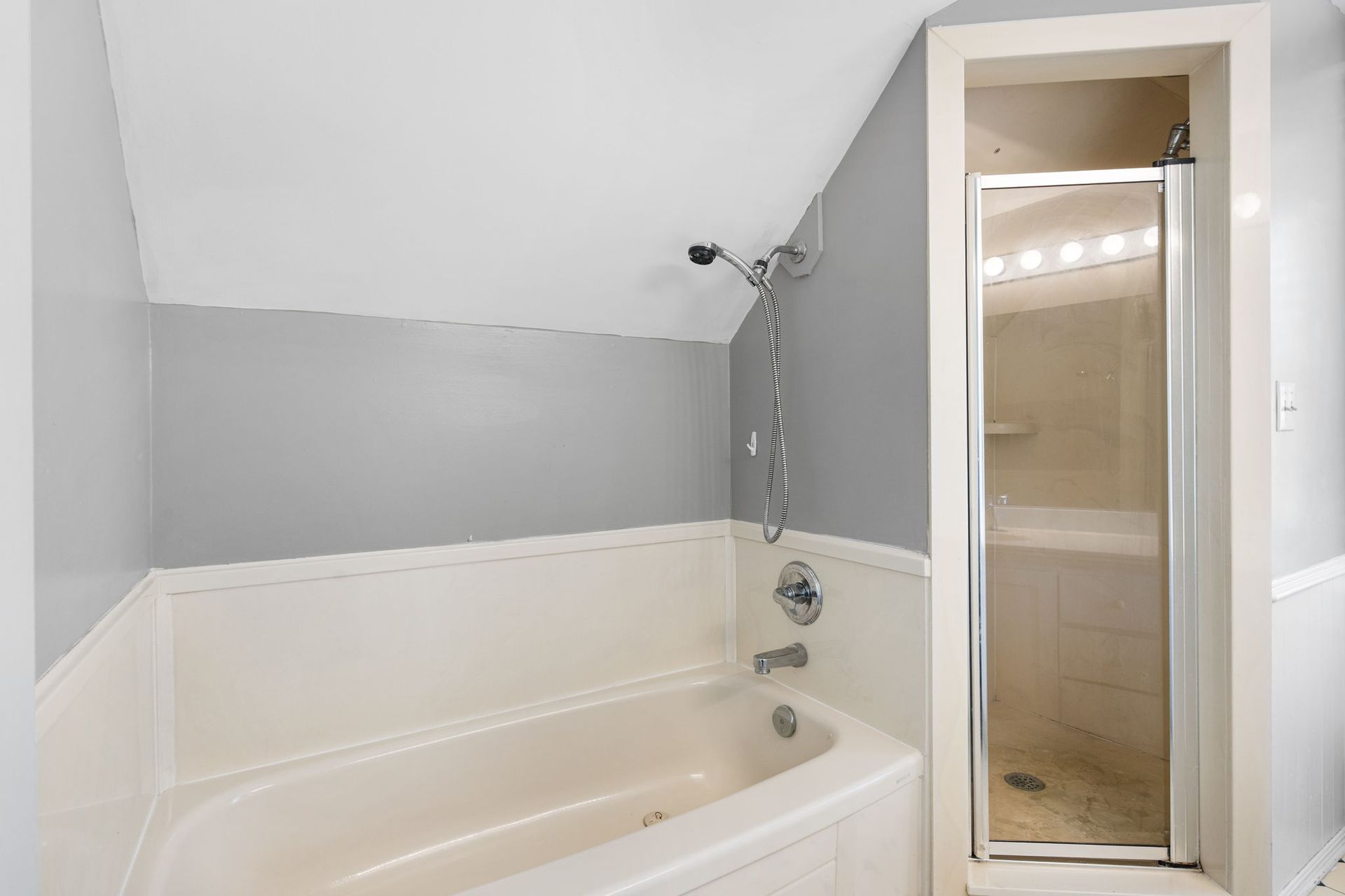Bathroom with bathtub, shower stall, and gray and white walls.