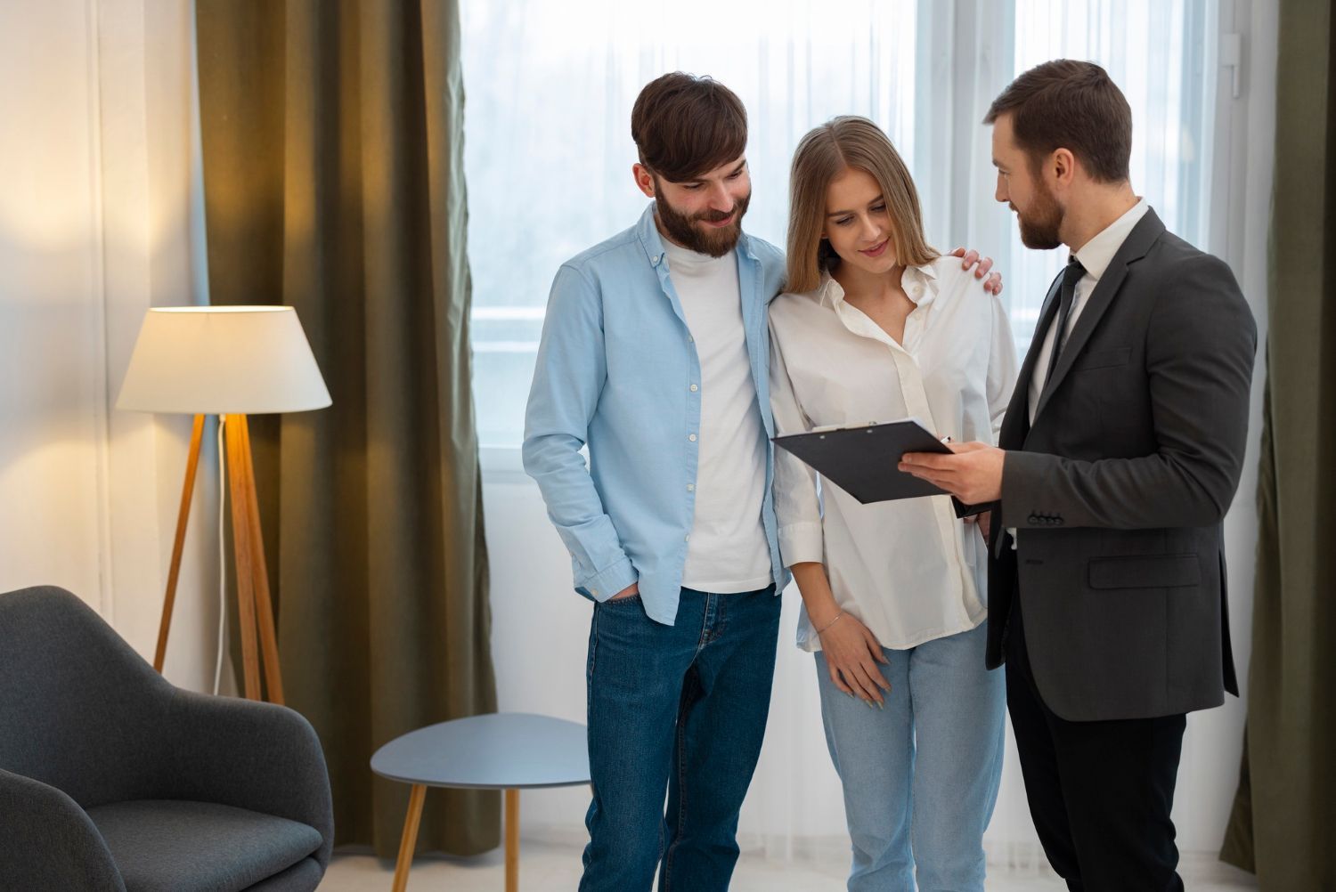 A man in a suit is talking to a couple in a living room.