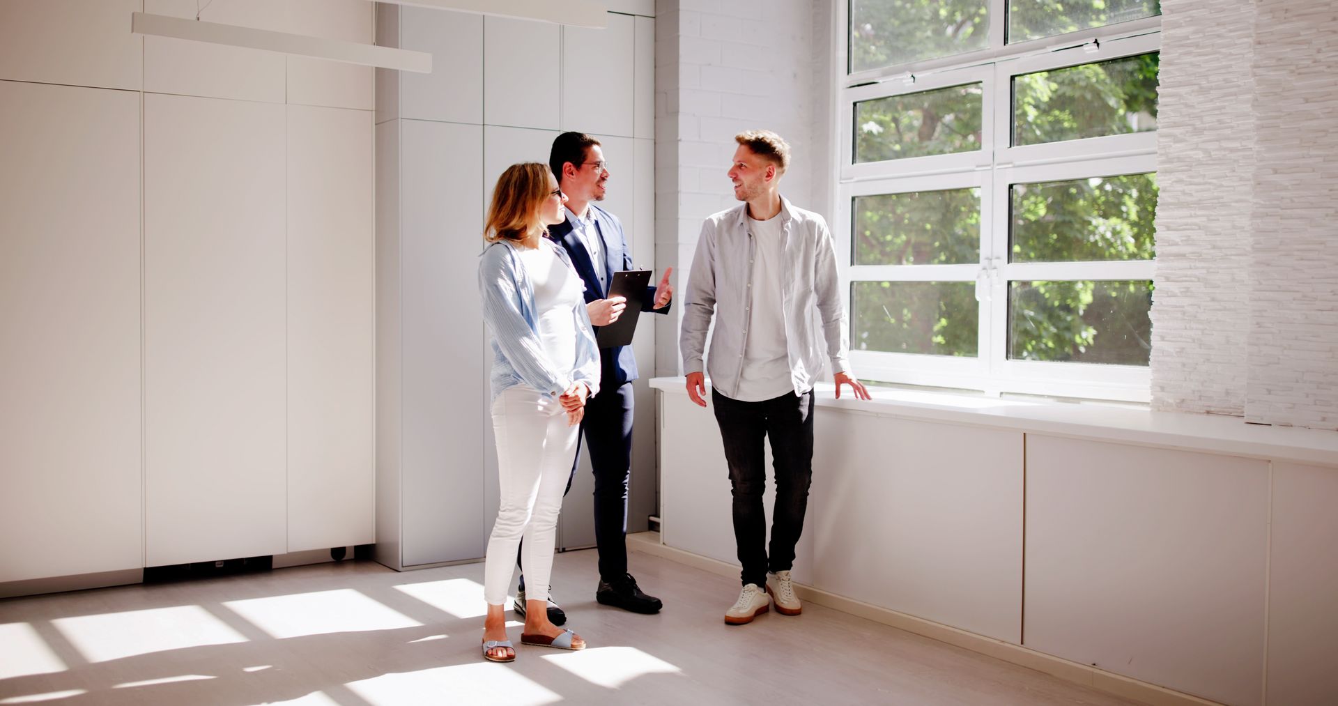 Real estate agent shows couple a potential apartment with large window.