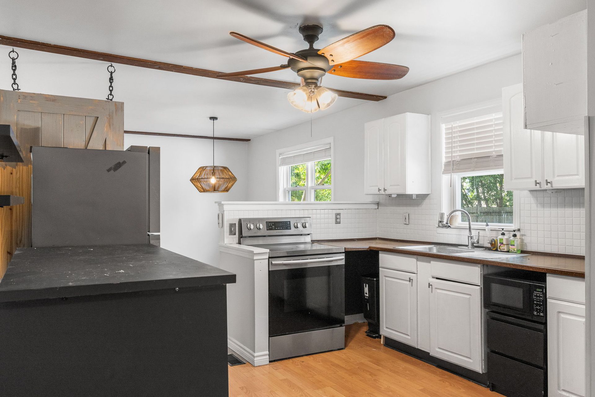 Kitchen with white cabinets, stainless steel appliances, and a wooden ceiling fan.