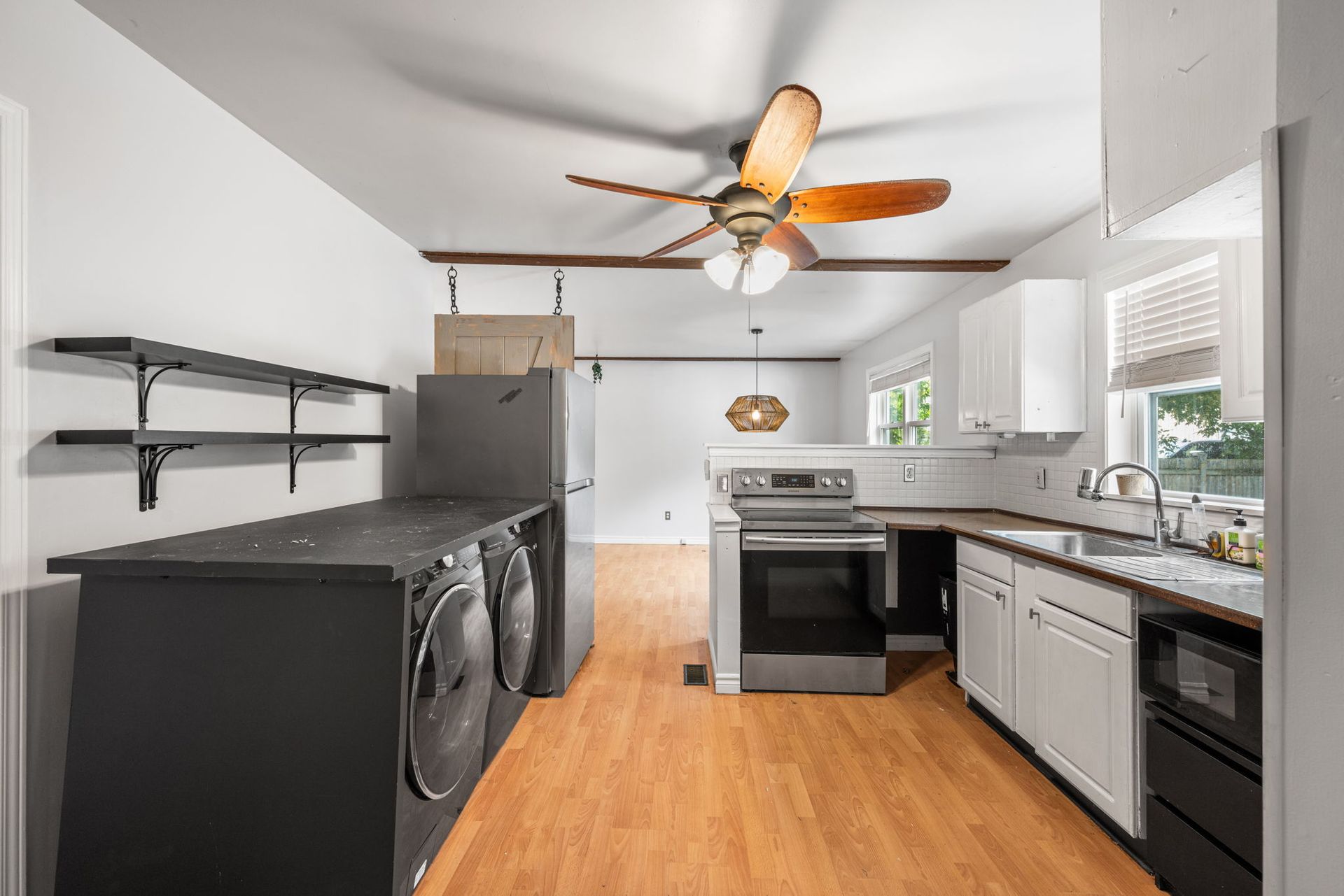 Kitchen with black and white cabinetry, stainless steel appliances, and light wood floors.