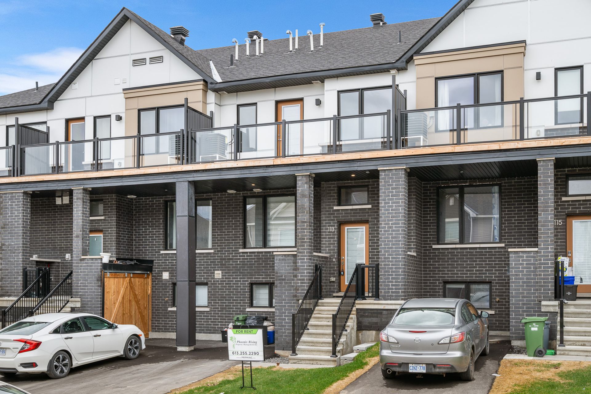 A white car is parked in front of a row of houses.