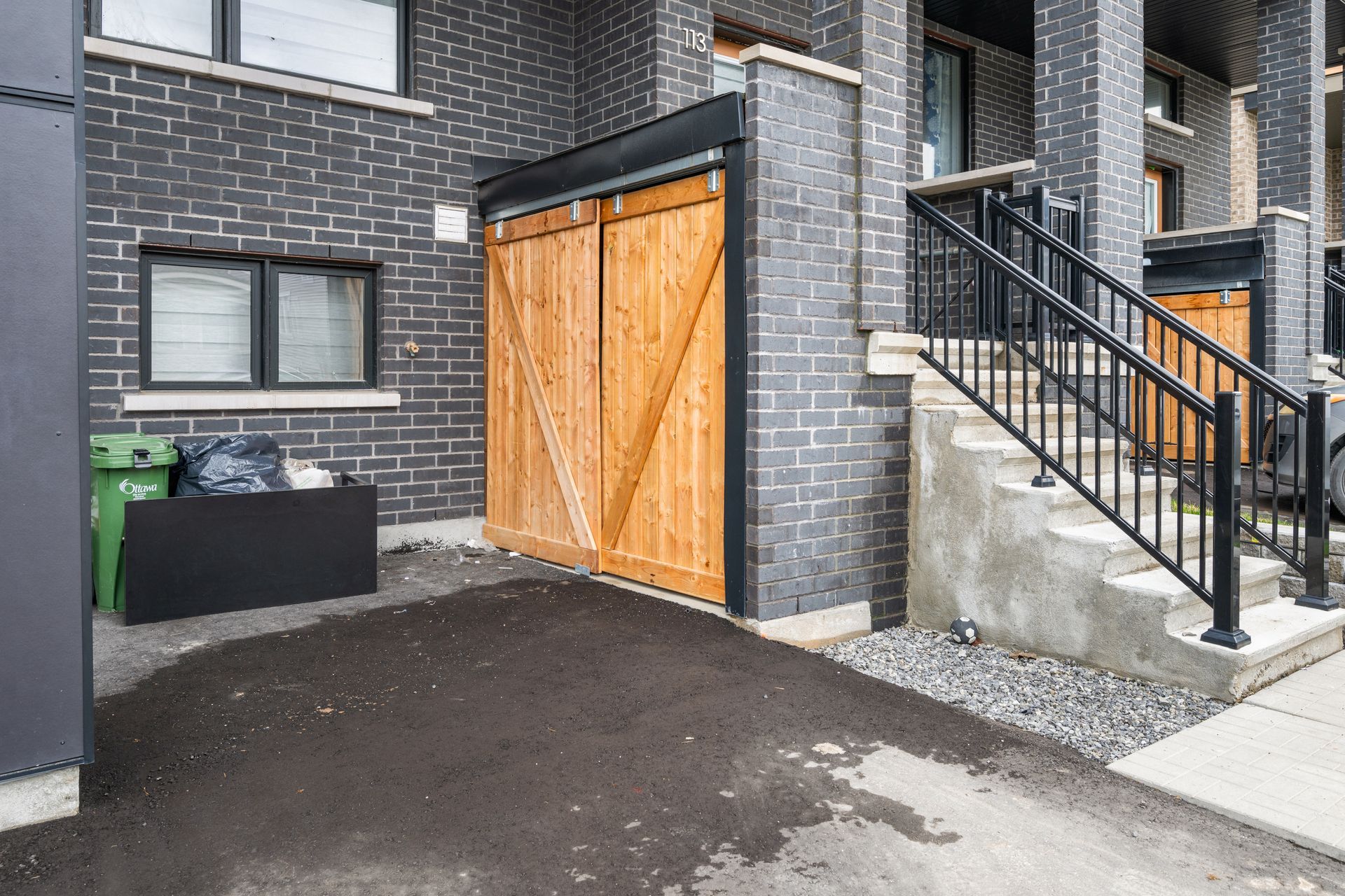 A brick house with a wooden garage door and stairs.
