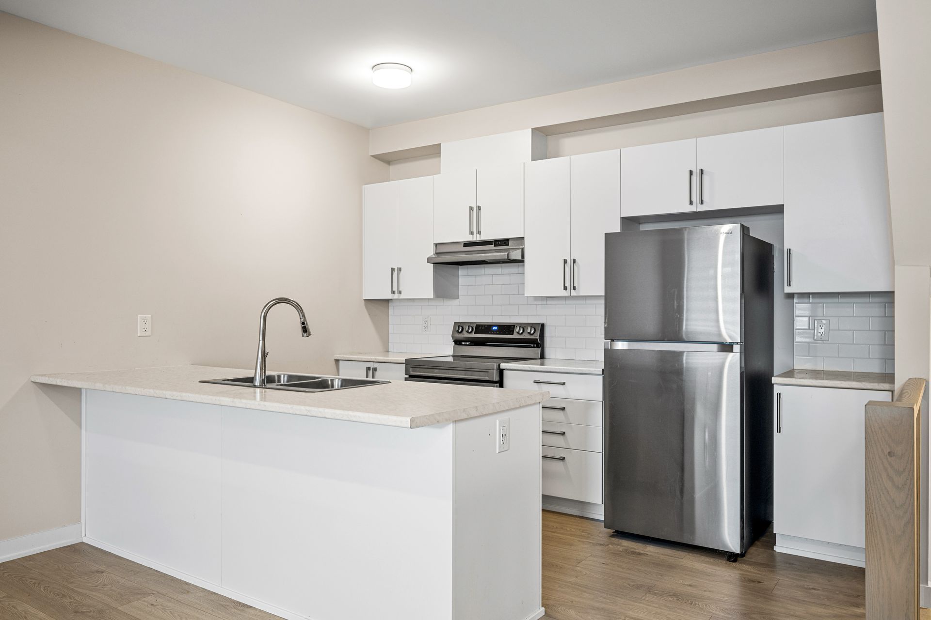 A kitchen with white cabinets and a stainless steel refrigerator.