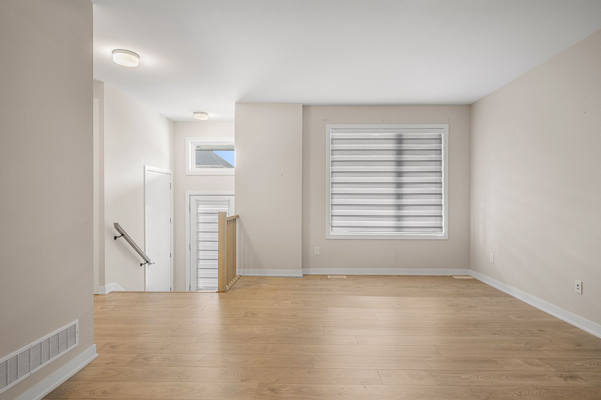 An empty living room with hardwood floors and a window.