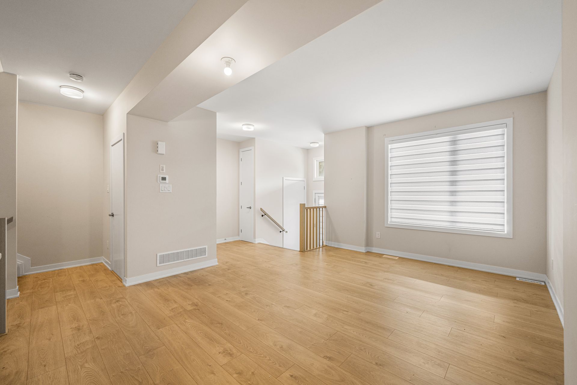 An empty living room with hardwood floors and a window.