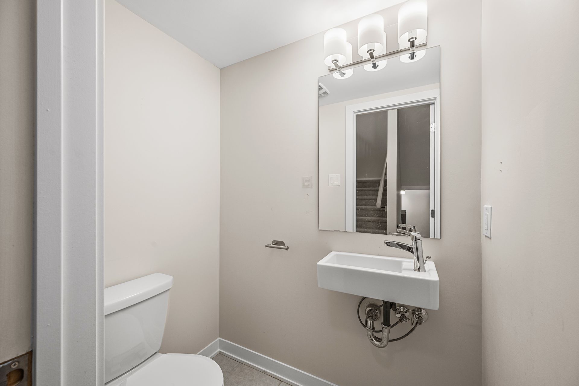 A bathroom with a toilet , sink and mirror.