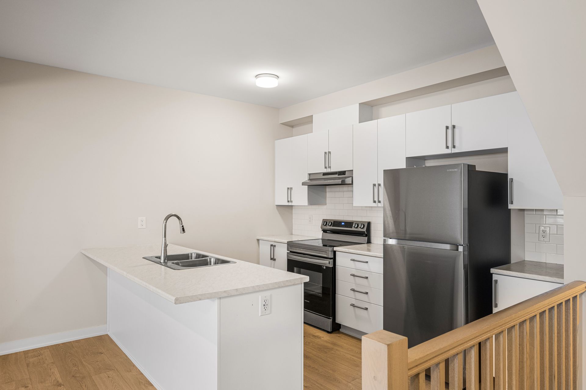 A kitchen with white cabinets , stainless steel appliances , a refrigerator and a sink.