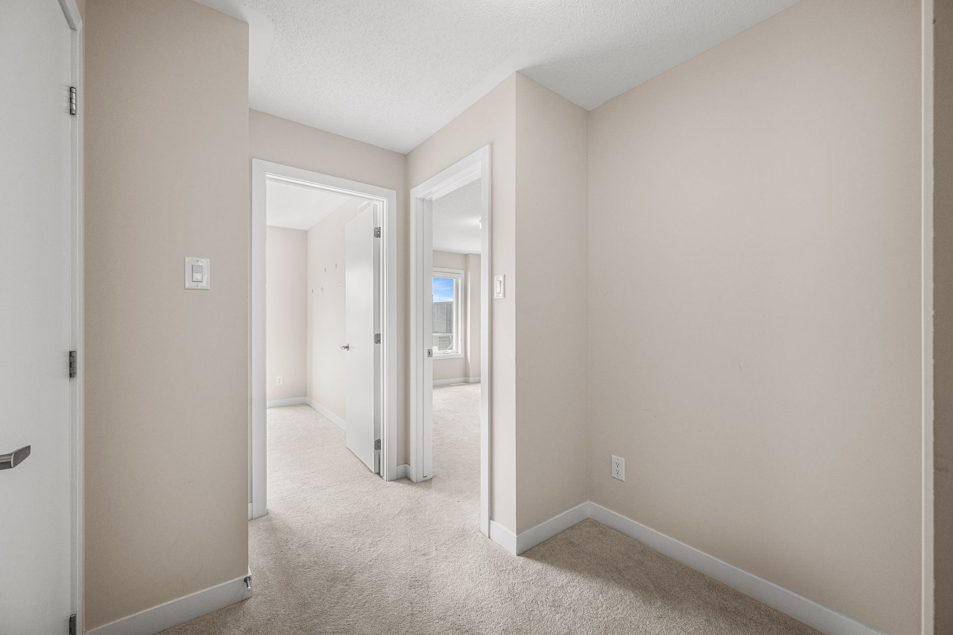 An empty room with a carpeted floor and beige walls in a house.