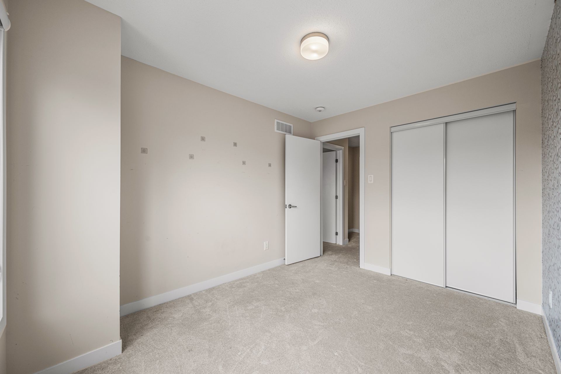 An empty bedroom with a carpeted floor and a closet.