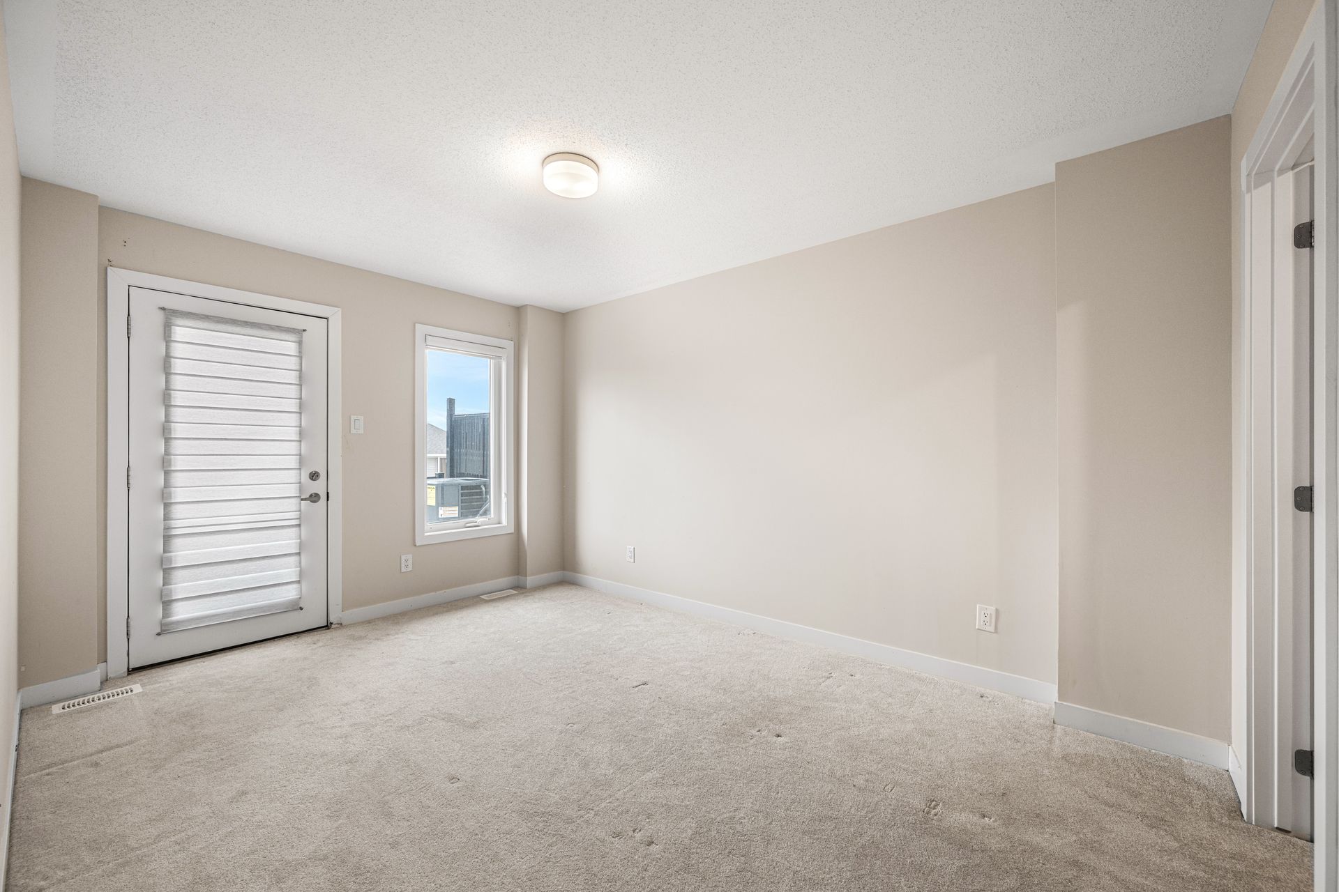 An empty living room with a carpeted floor and two windows.