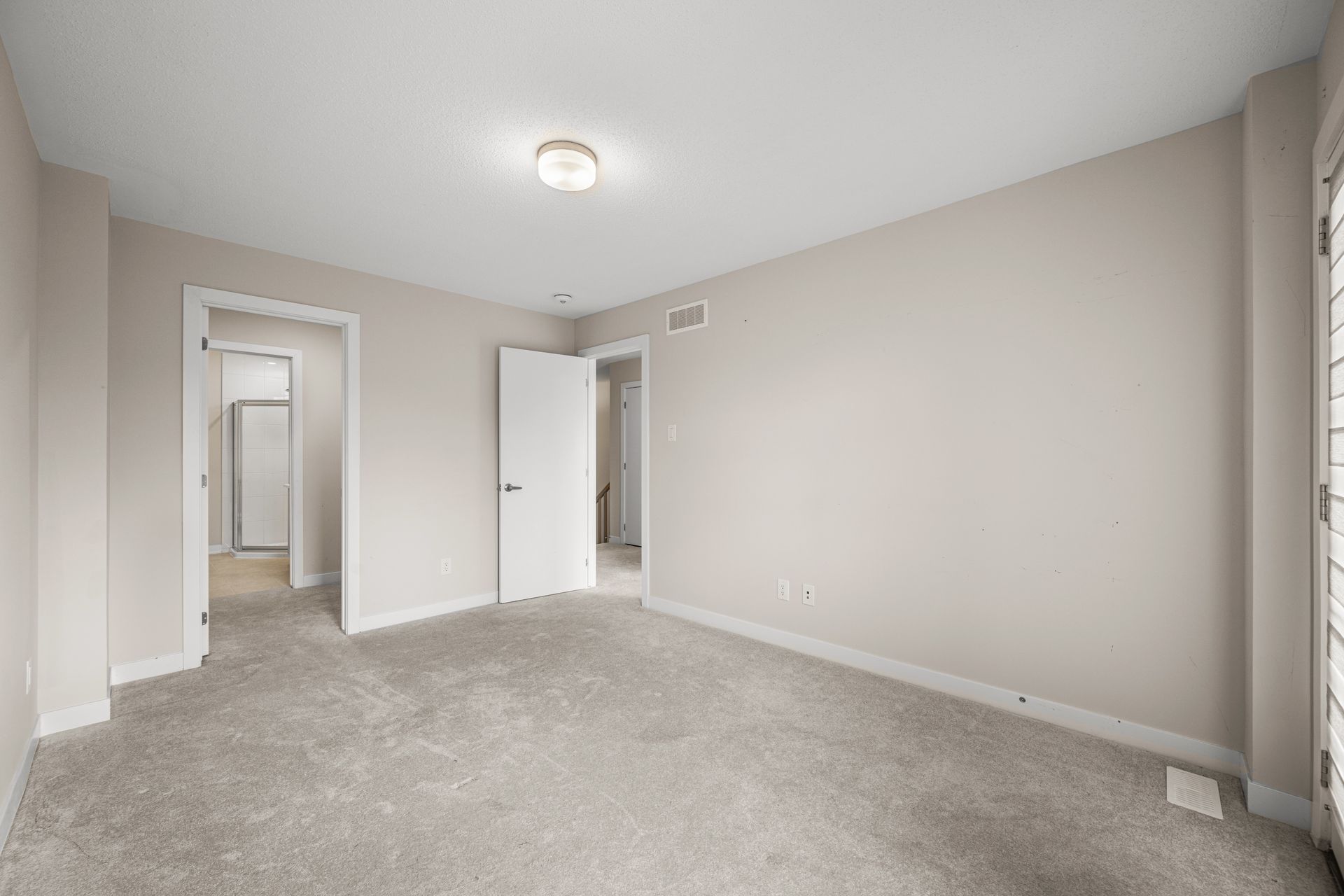 An empty bedroom with a carpeted floor and white walls.