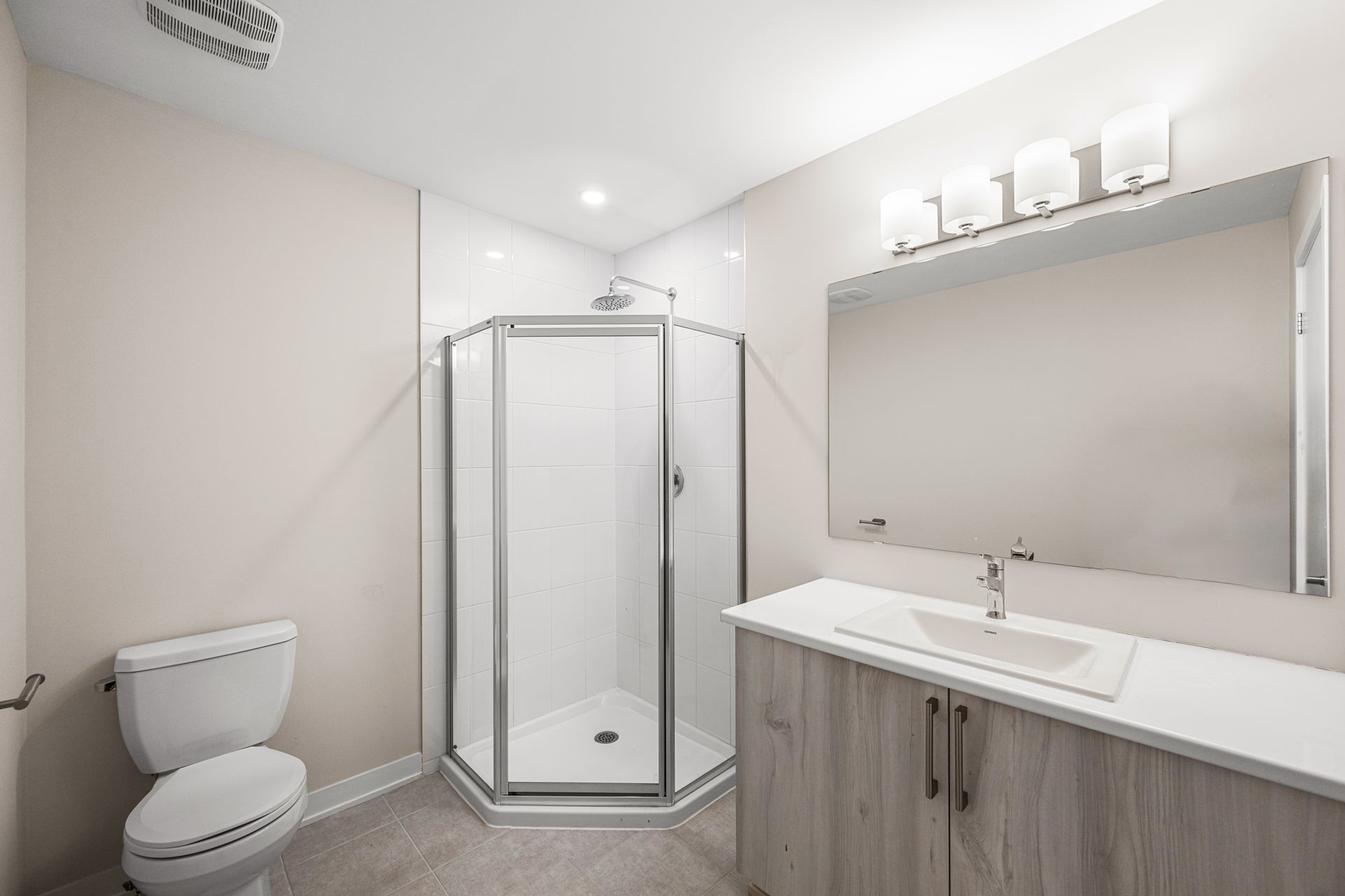 A bathroom with a toilet , sink , shower and mirror.