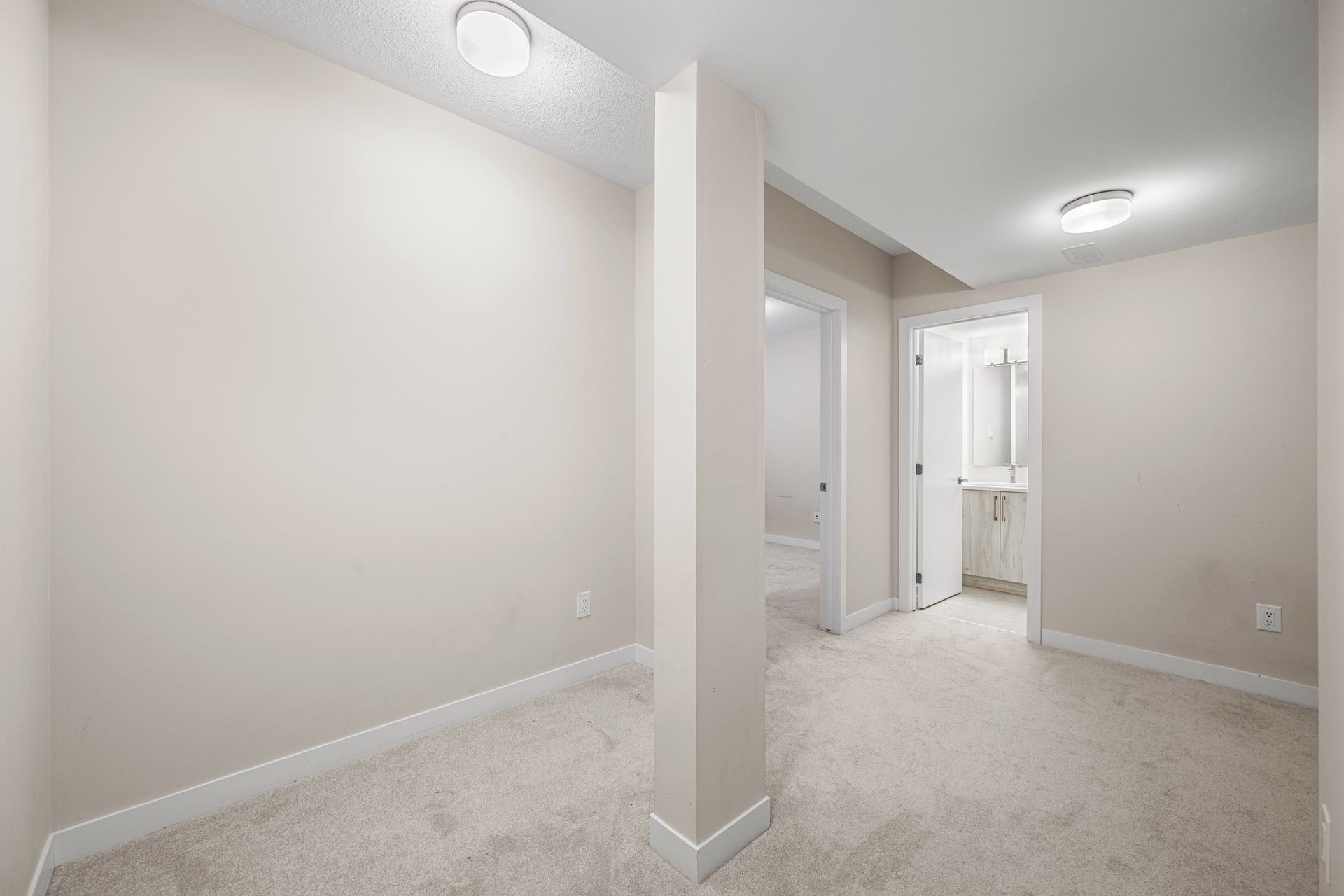 An empty room with white walls and a carpeted floor.