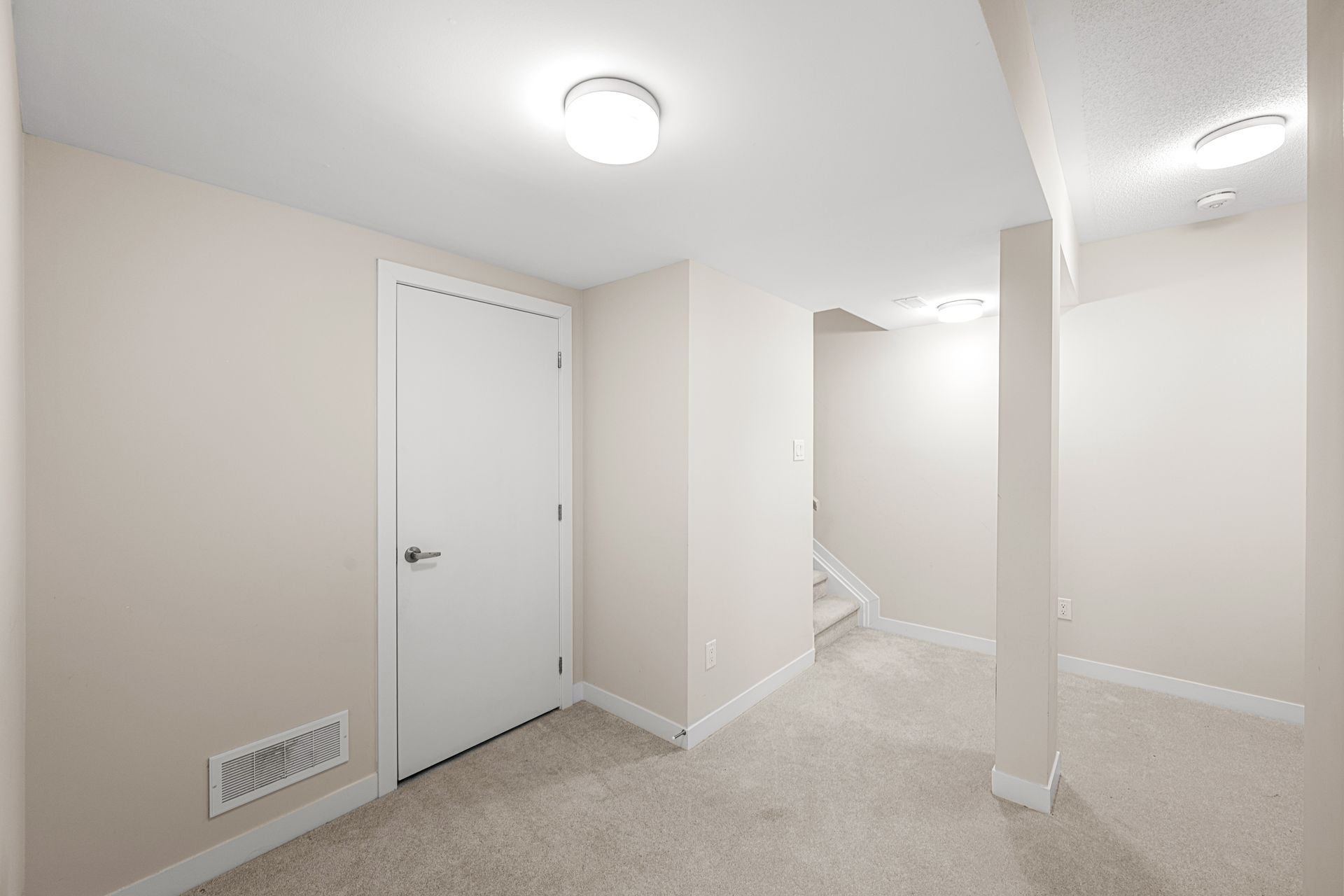 An empty basement with a door and stairs.