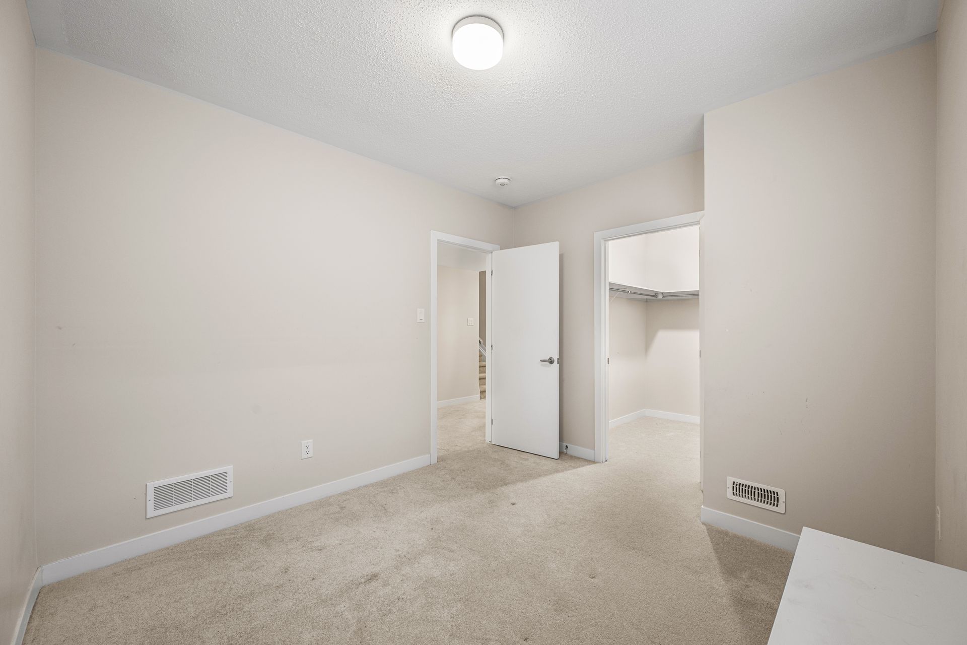 An empty bedroom with a carpeted floor and a walk in closet.