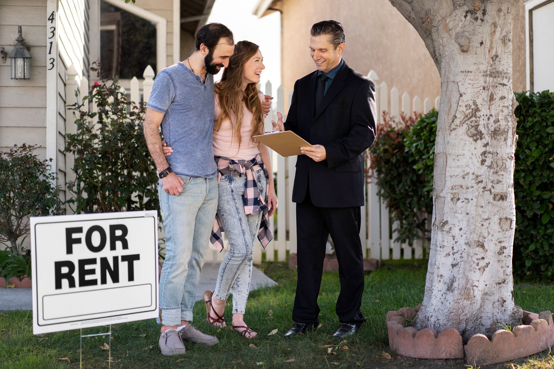 Couple and realtor reviewing rental agreement next to a 