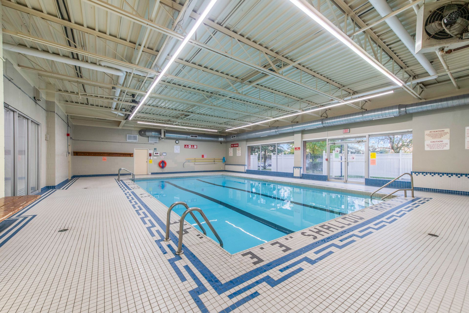 A large indoor swimming pool with a blue and white tile floor.